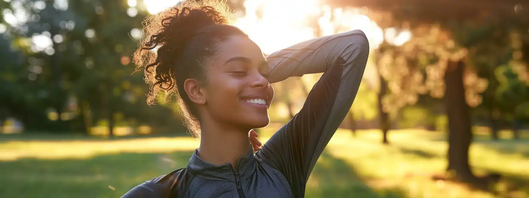 a woman in athletic gear joyfully stretching in a sunlit park, showcasing the connection between exercise and symptom relief for endometriosis.