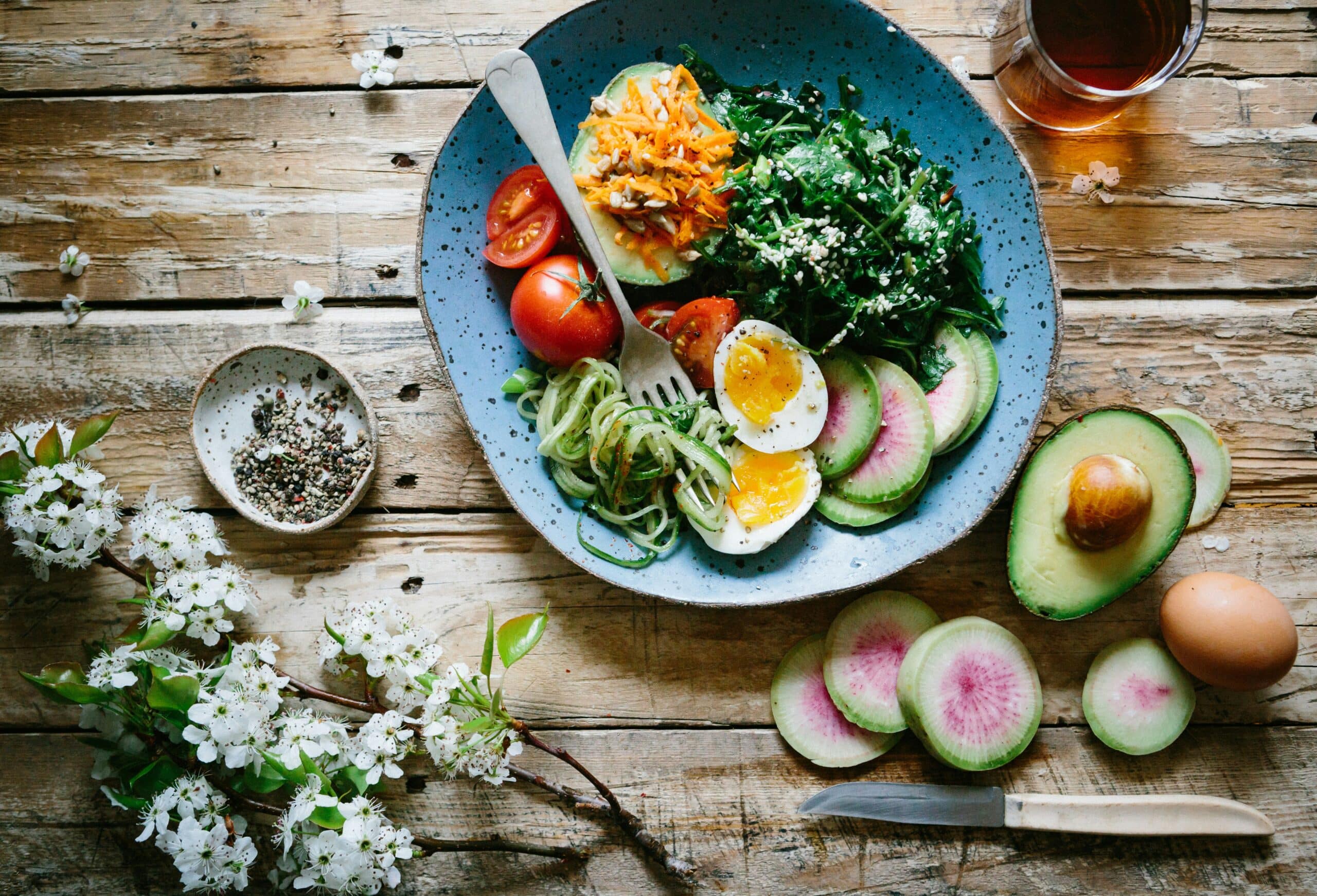 A colorful plant-based meal with fresh vegetables, eggs, and avocado on a rustic wooden table, illustrating the science behind a plant-based diet and its health benefits.