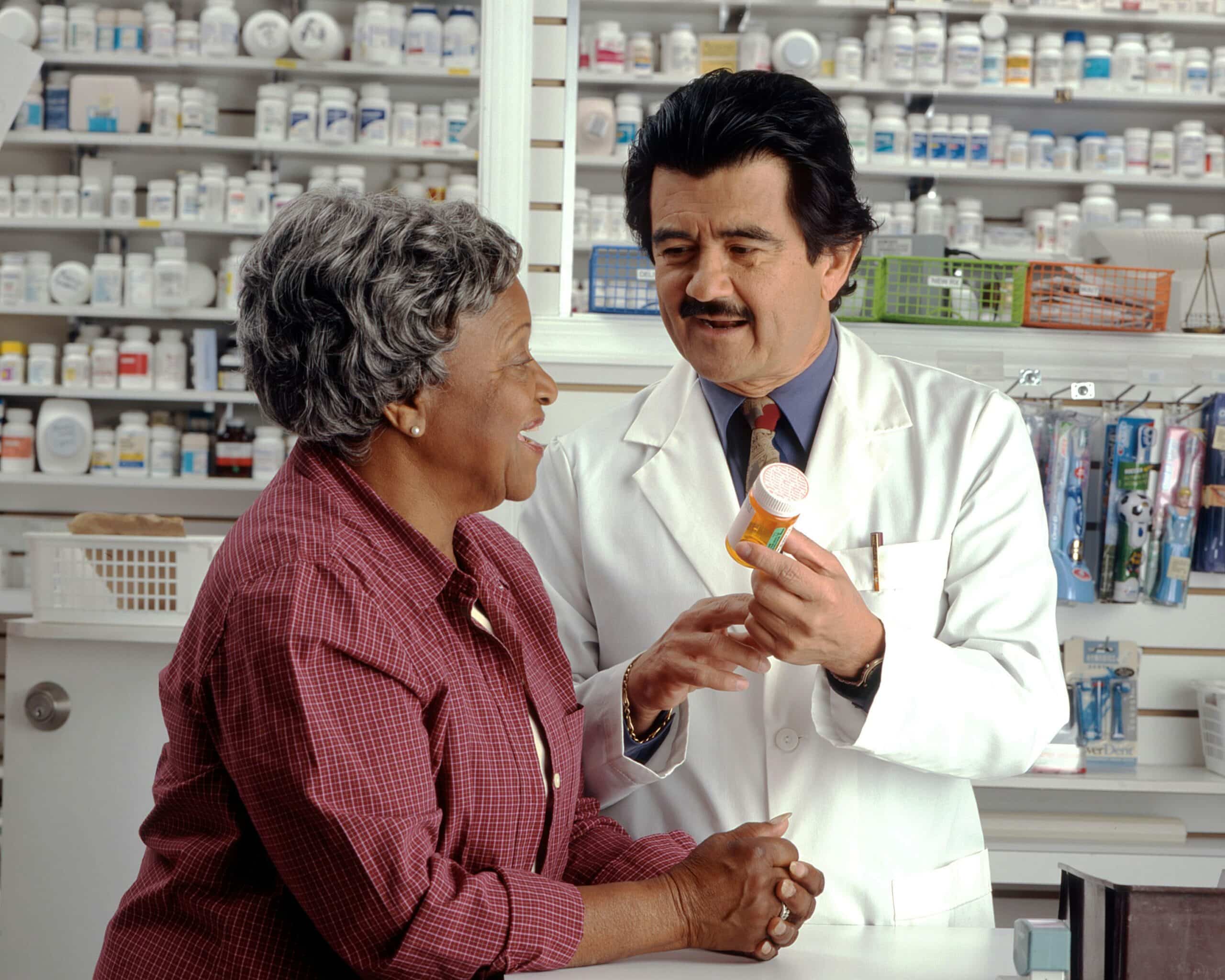 A pharmacist explaining medication to a patient in a pharmacy, highlighting the importance of discussing prescription costs as part of endometriosis treatment planning.