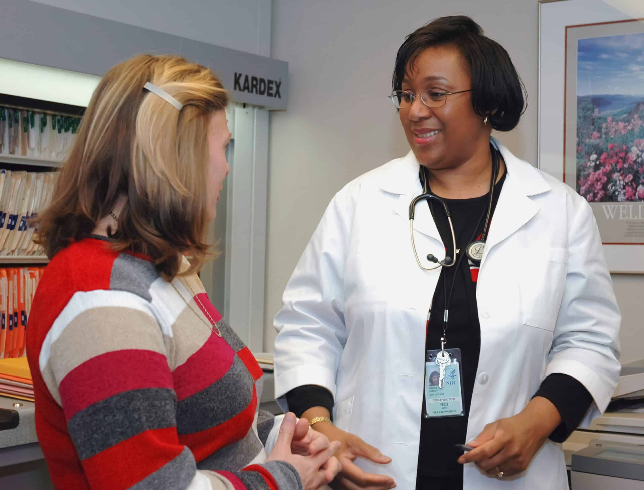 A doctor in a white coat speaking with a patient, representing the importance of understanding endometriosis and its symptoms through professional medical consultation and support.