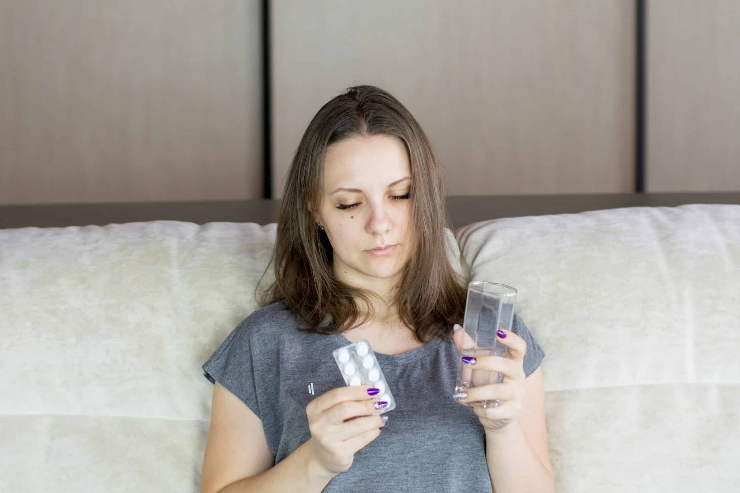 Person holding medication and a glass of water