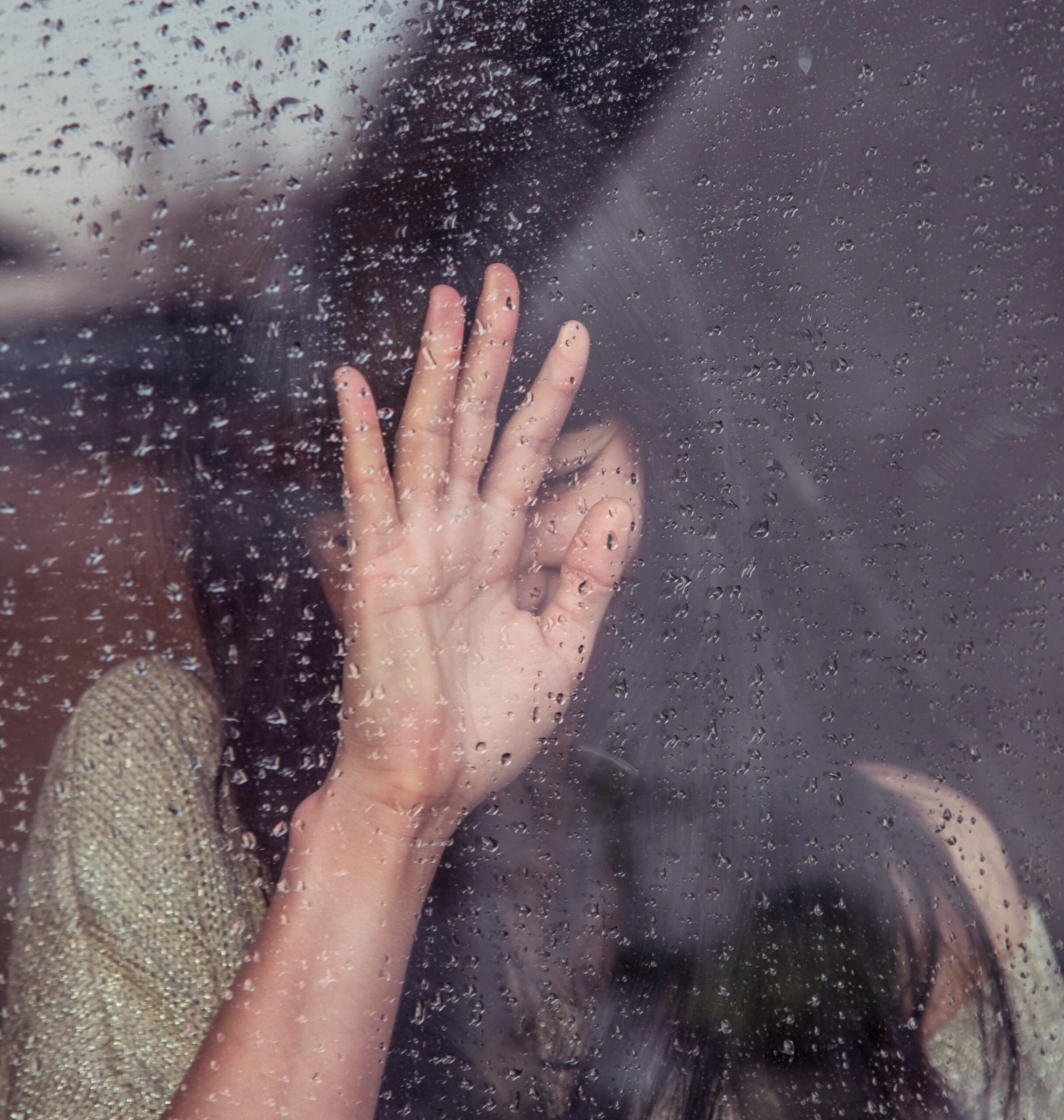 A hand pressed against a rainy window, conveying a sense of contemplation or emotional struggle, which could reflect the internal experience of dealing with endometriosis pain.