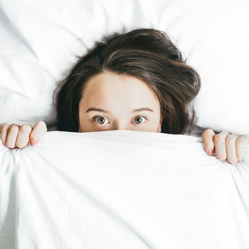 a woman covering her face with a sheet