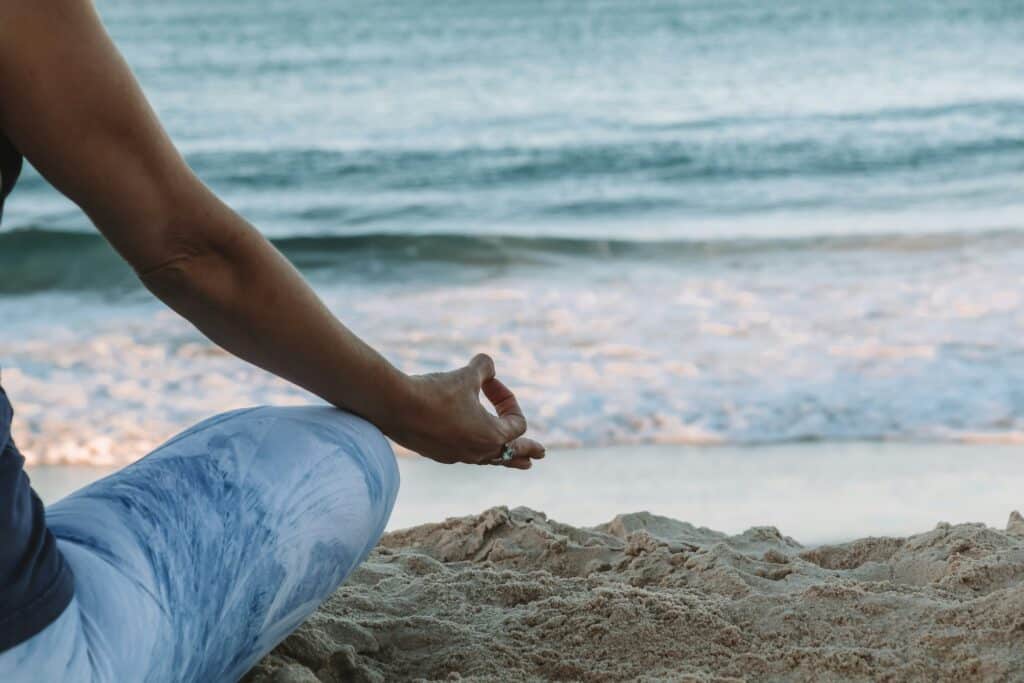 a woman meditating at the beach