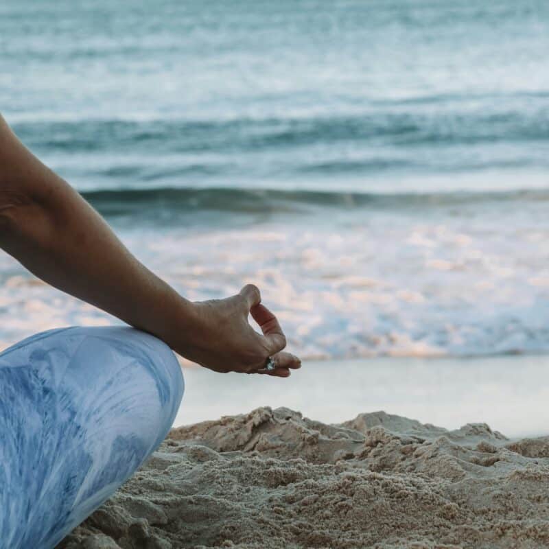 a woman meditating at the beach