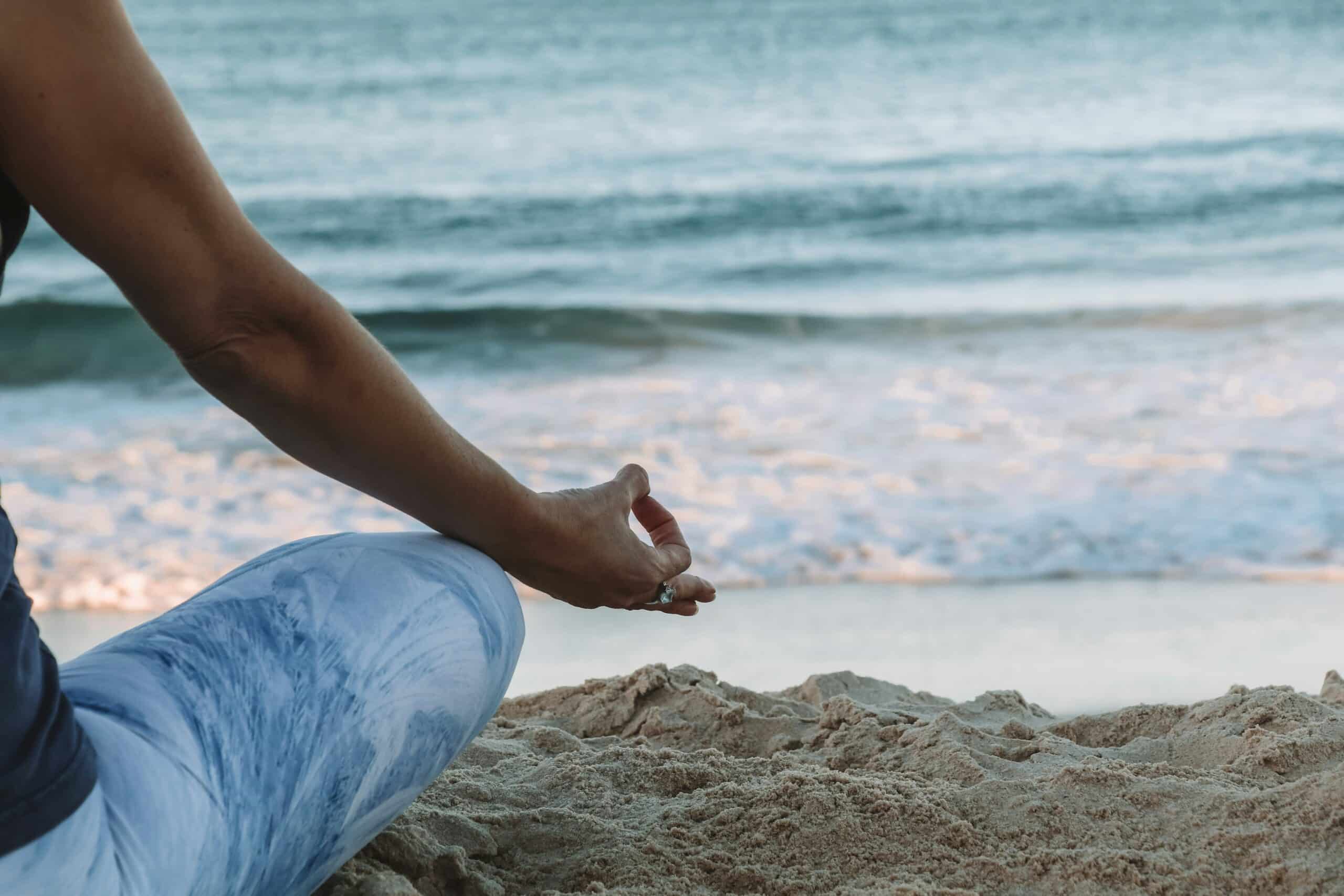 a woman meditating at the beach