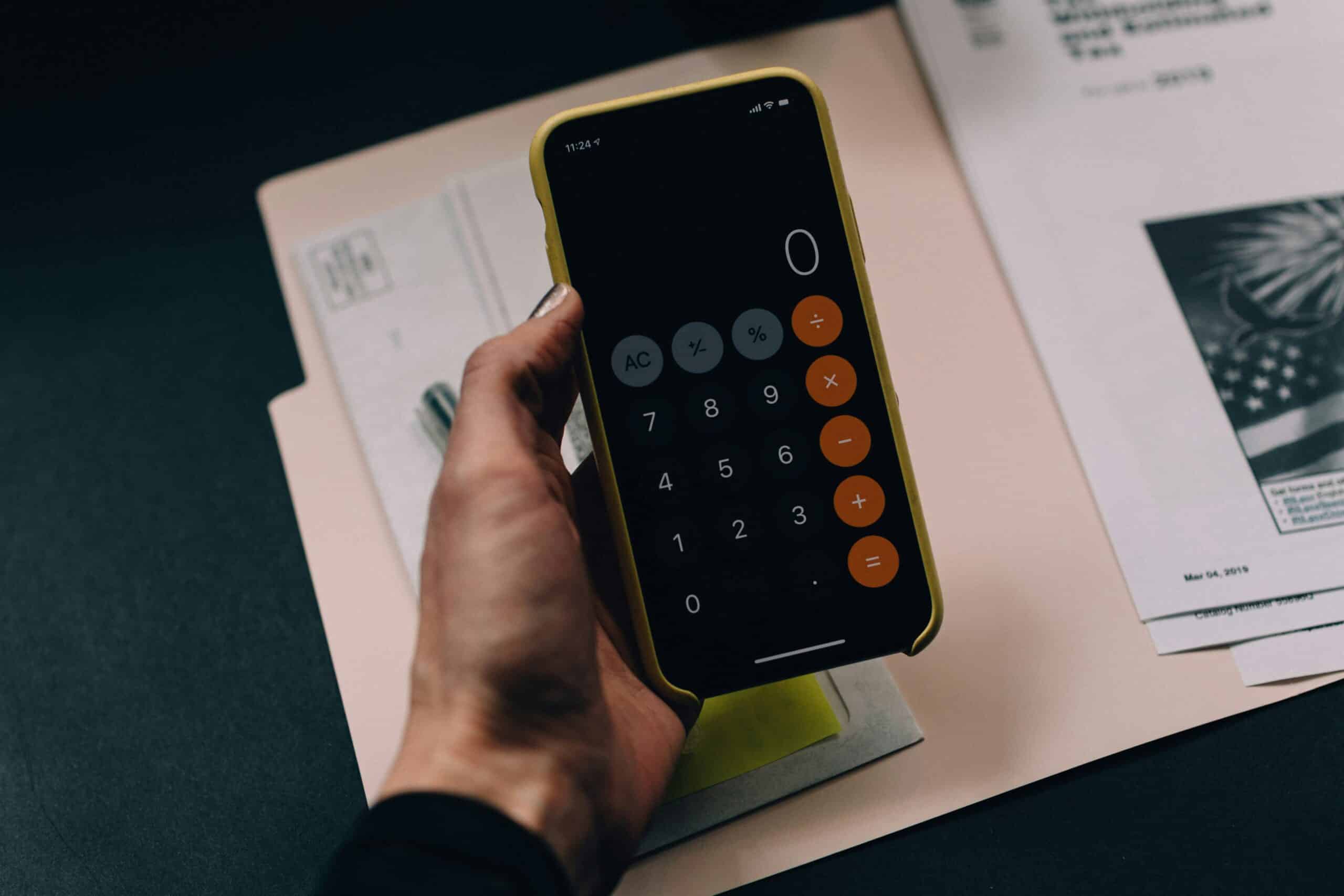 A person using a smartphone calculator, potentially evaluating costs related to endometriosis treatment, with paperwork in the background.