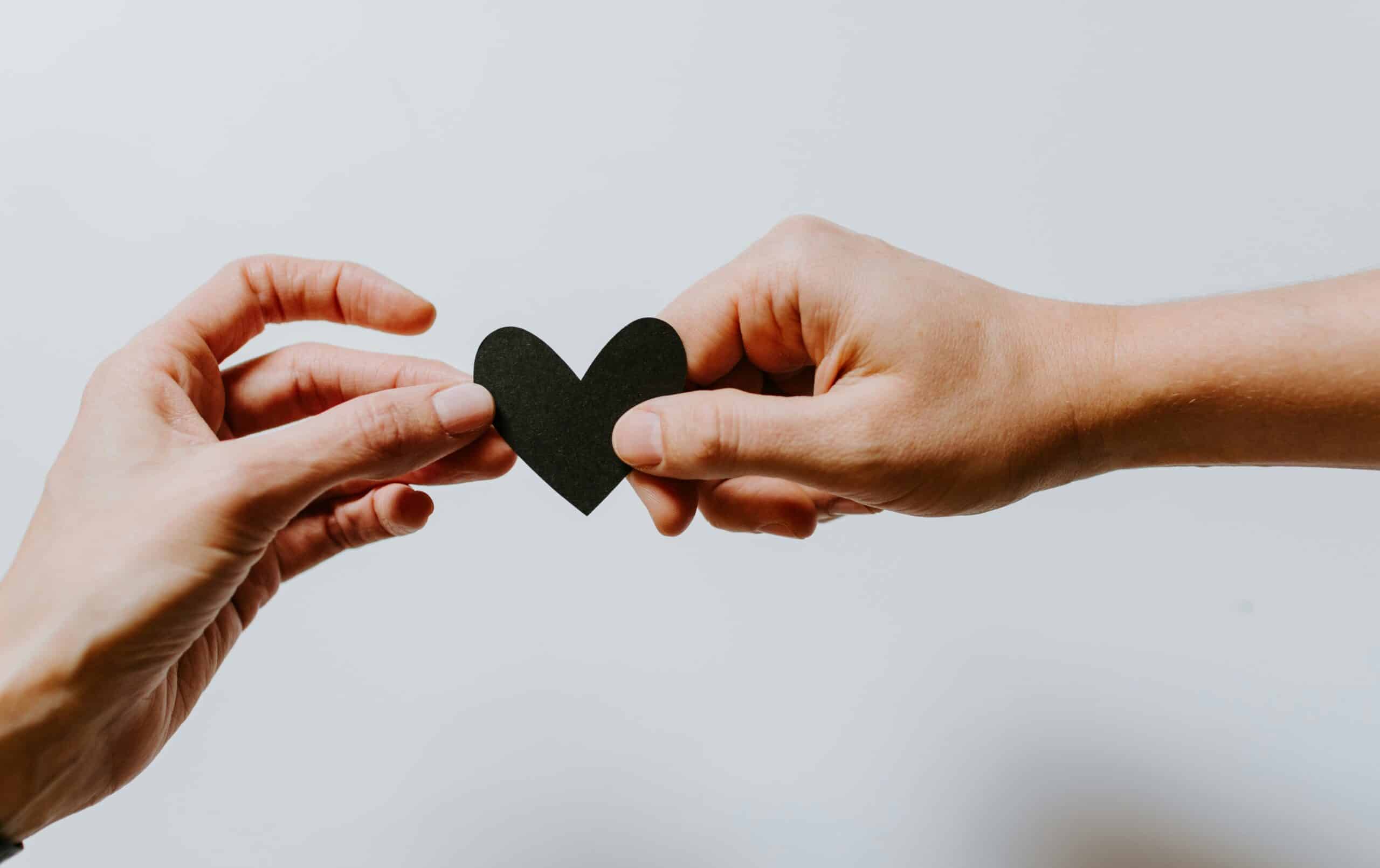 two hands holding a paper cut heart