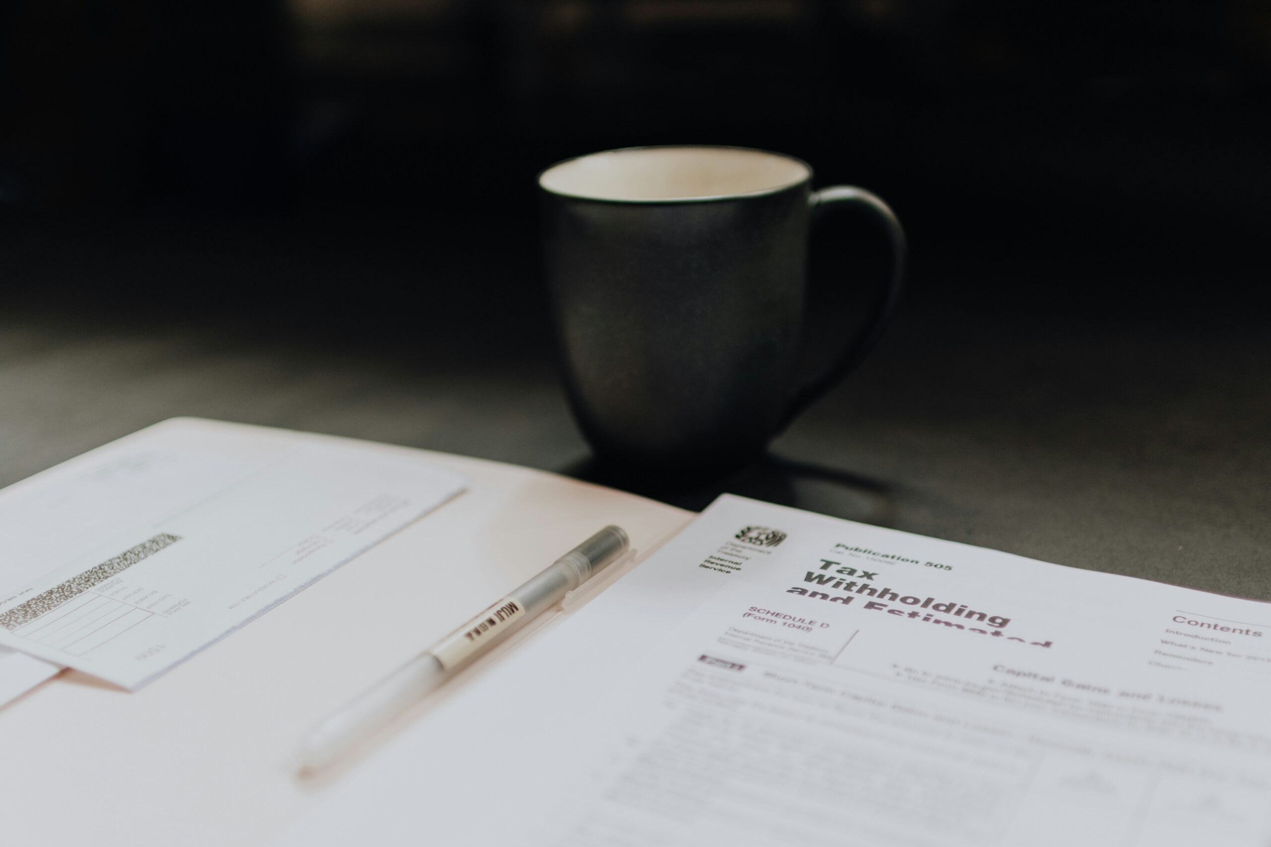 A close-up of a tax form, pen, and a cup of coffee, symbolizing the review of financial details and hidden costs in a treatment plan.