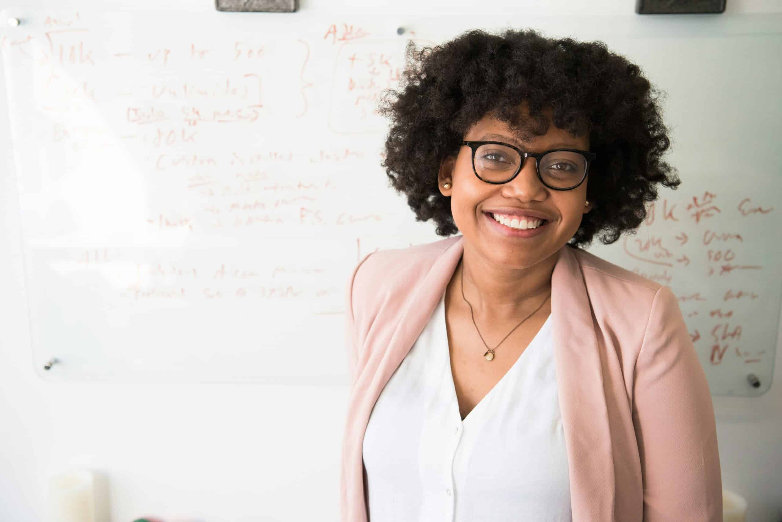 A smiling person doctor in front of a whiteboard, exuding a positive and professional demeanor, which can reflect a productive and goal-oriented mindset.