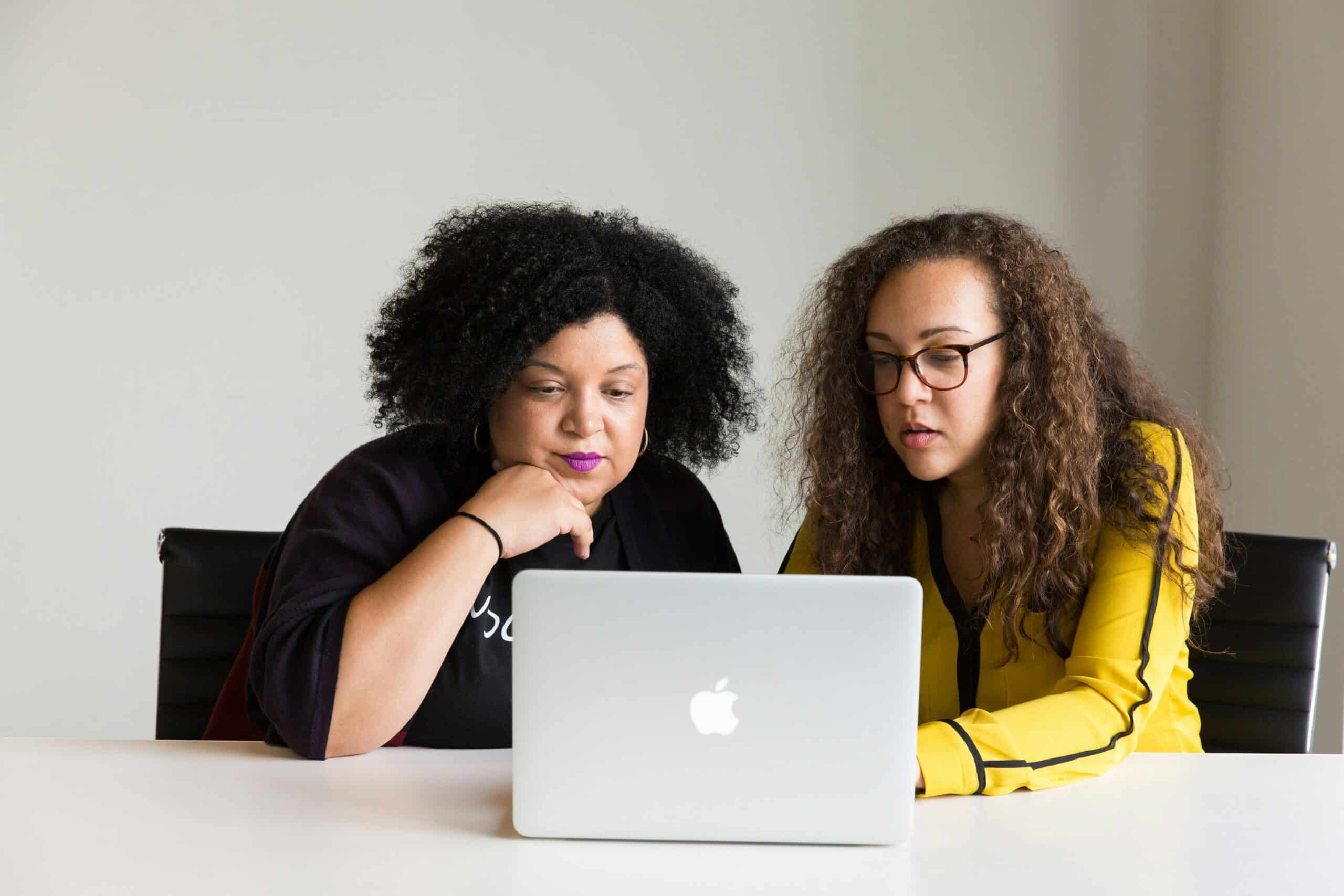 Two women collaborating over a laptop, reflecting the research or work process in the context of setting up a crowdfunding campaign for endometriosis care.