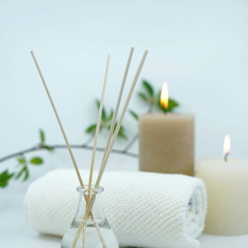 A calming spa setup with scented reed diffusers, lit candles, and rolled towels, symbolizing the soothing benefits of massage therapy as an effective approach for managing endometriosis symptoms.