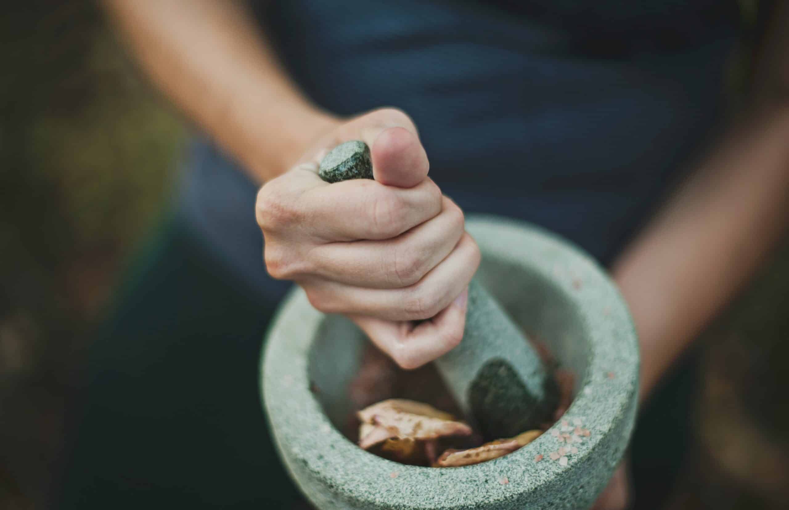 A close-up of a person using a stone mortar and pestle to grind herbs, symbolizing the use of natural supplements and holistic approaches in nutrition for endometriosis pain management. - Rachael Haverland Site A close-up of a person using a stone mortar and pestle to grind herbs, symbolizing the use of natural supplements and holistic approaches in nutrition for endometriosis pain management.