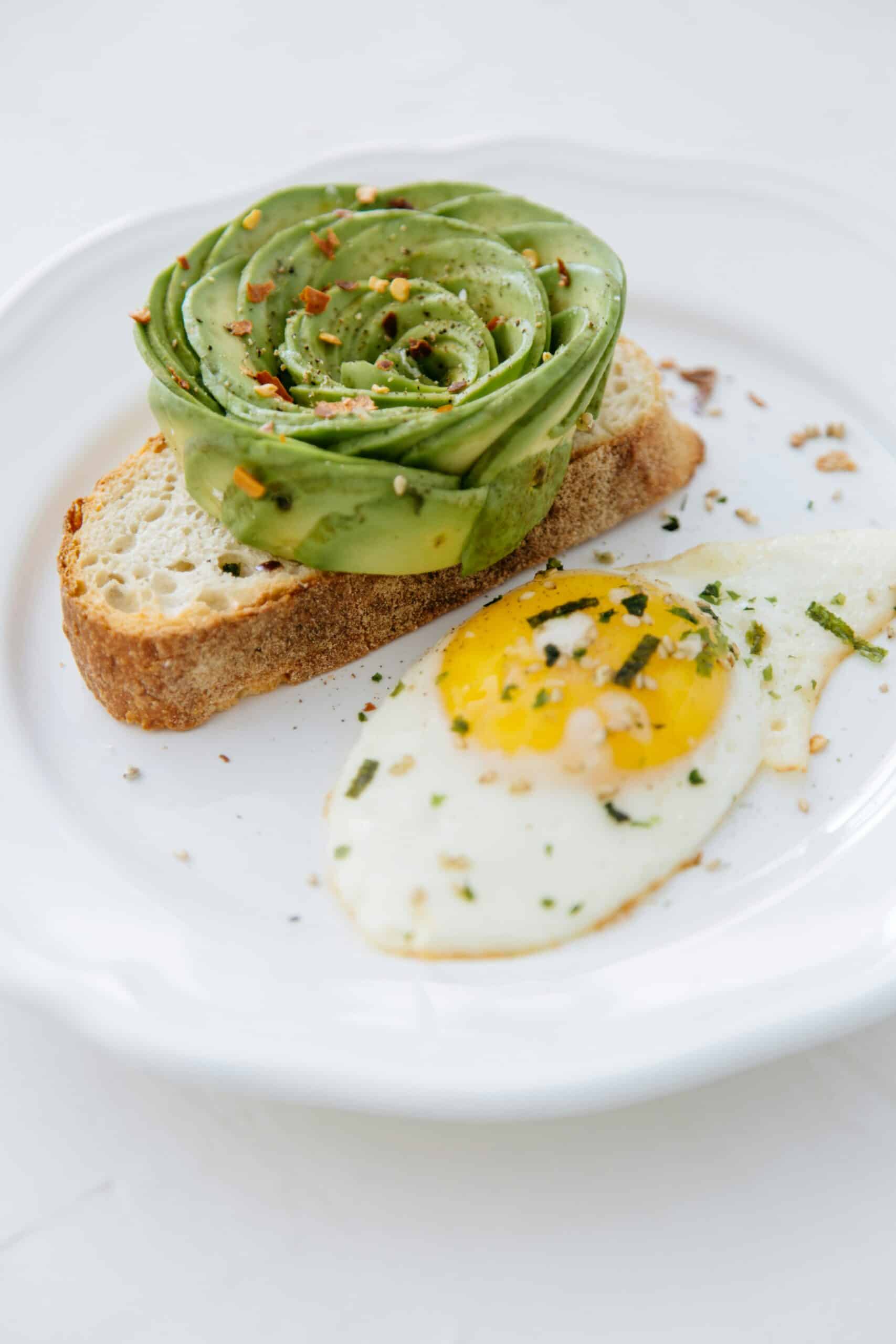 A plate with avocado toast and a fried egg, illustrating practical tips for managing dairy intake by incorporating balanced, nutritious alternatives in daily meals.