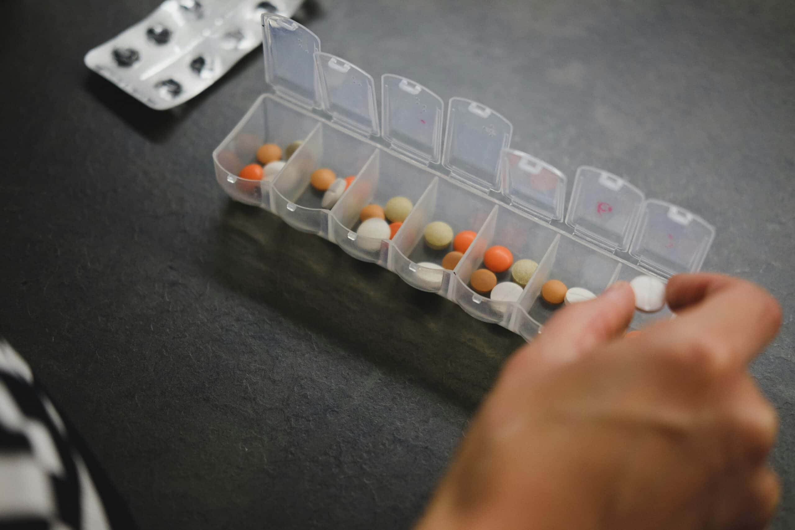 A person organizing a variety of supplements in a weekly pill organizer, suggesting a personalized approach to managing endometriosis symptoms with tailored nutritional support. - Rachael Haverland Site A person organizing a variety of supplements in a weekly pill organizer, suggesting a personalized approach to managing endometriosis symptoms with tailored nutritional support.