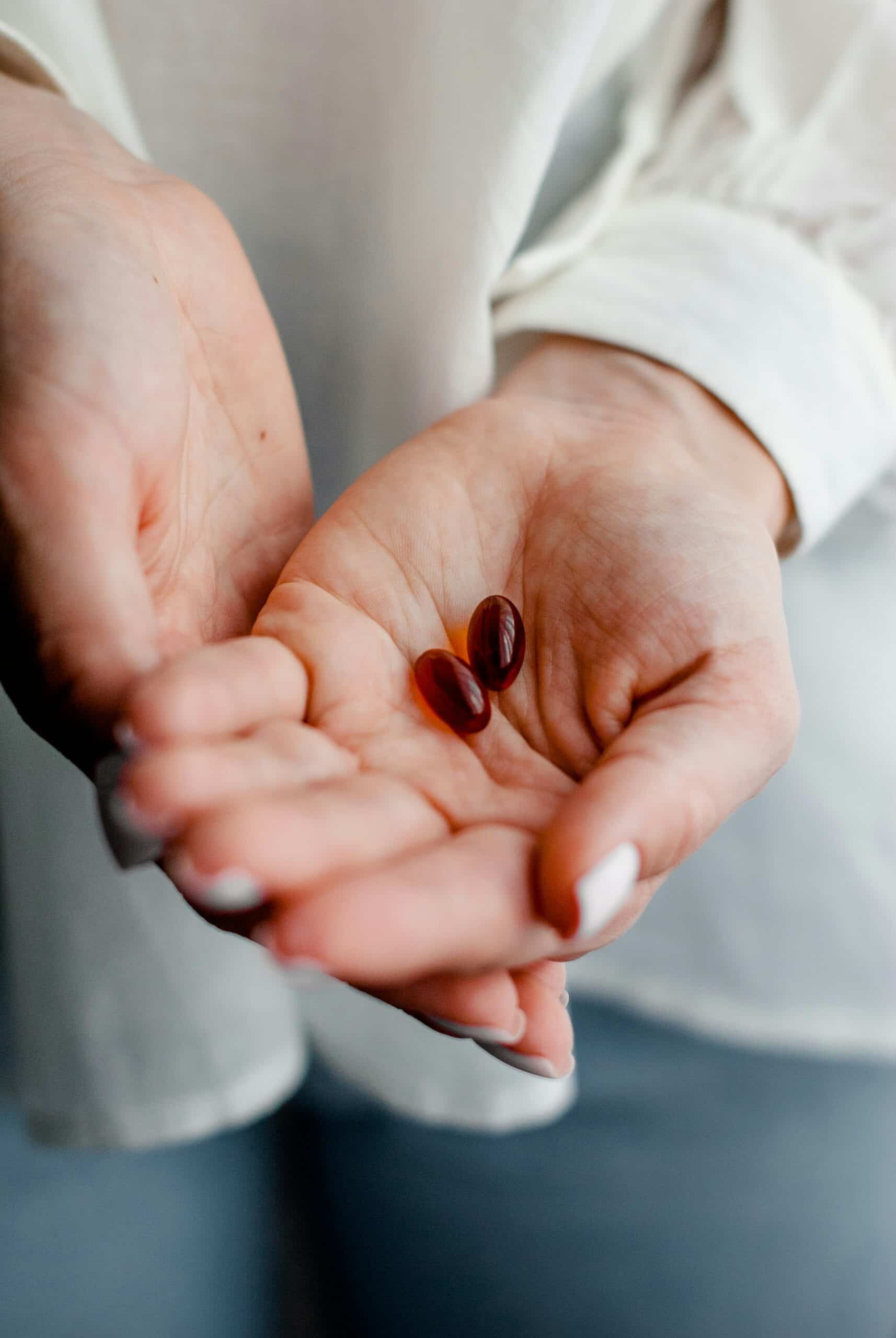 A person holding two softgel capsules in their open palm, symbolizing the role of vitamins in alleviating endometriosis symptoms and supporting overall wellness. - Rachael Haverland Site A person holding two softgel capsules in their open palm, symbolizing the role of vitamins in alleviating endometriosis symptoms and supporting overall wellness.