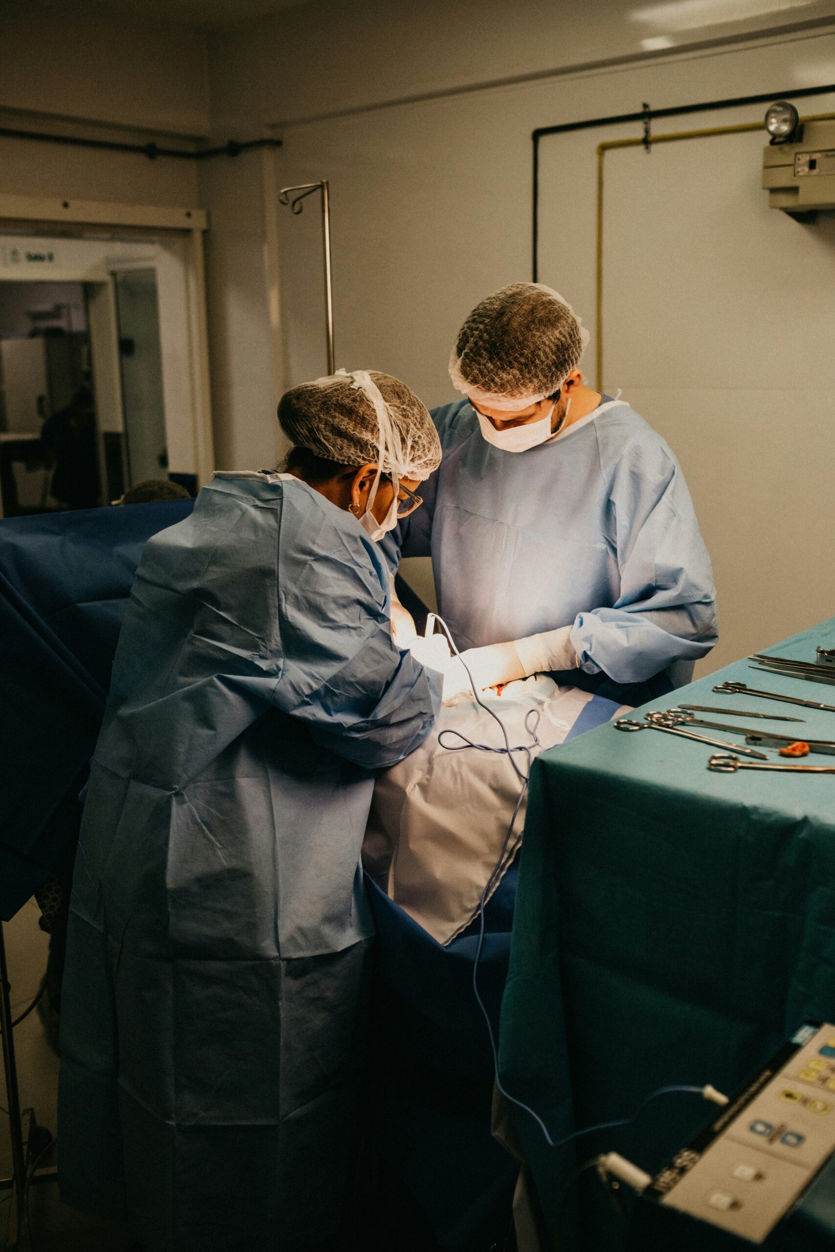 Surgeons in sterile blue gowns and masks performing a surgical procedure in an operating room, highlighting the precision and care involved in endometriosis excision surgery. - Rachael Haverland Site Surgeons in sterile blue gowns and masks performing a surgical procedure in an operating room, highlighting the precision and care involved in endometriosis excision surgery.