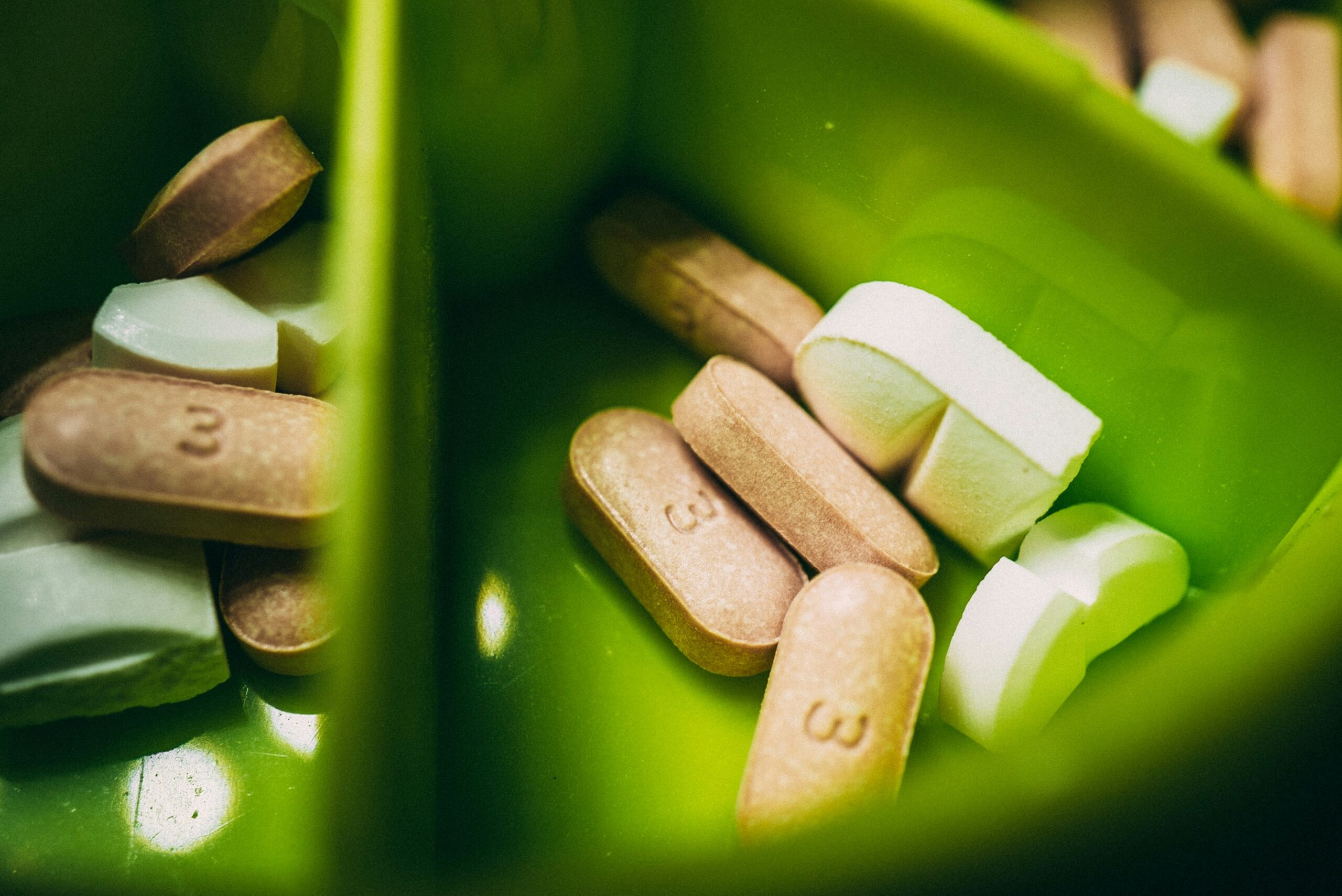A close-up of various pills in a green pill organizer, symbolizing medication and pain management strategies following endometriosis surgery. - Rachael Haverland Site A close-up of various pills in a green pill organizer, symbolizing medication and pain management strategies following endometriosis surgery.