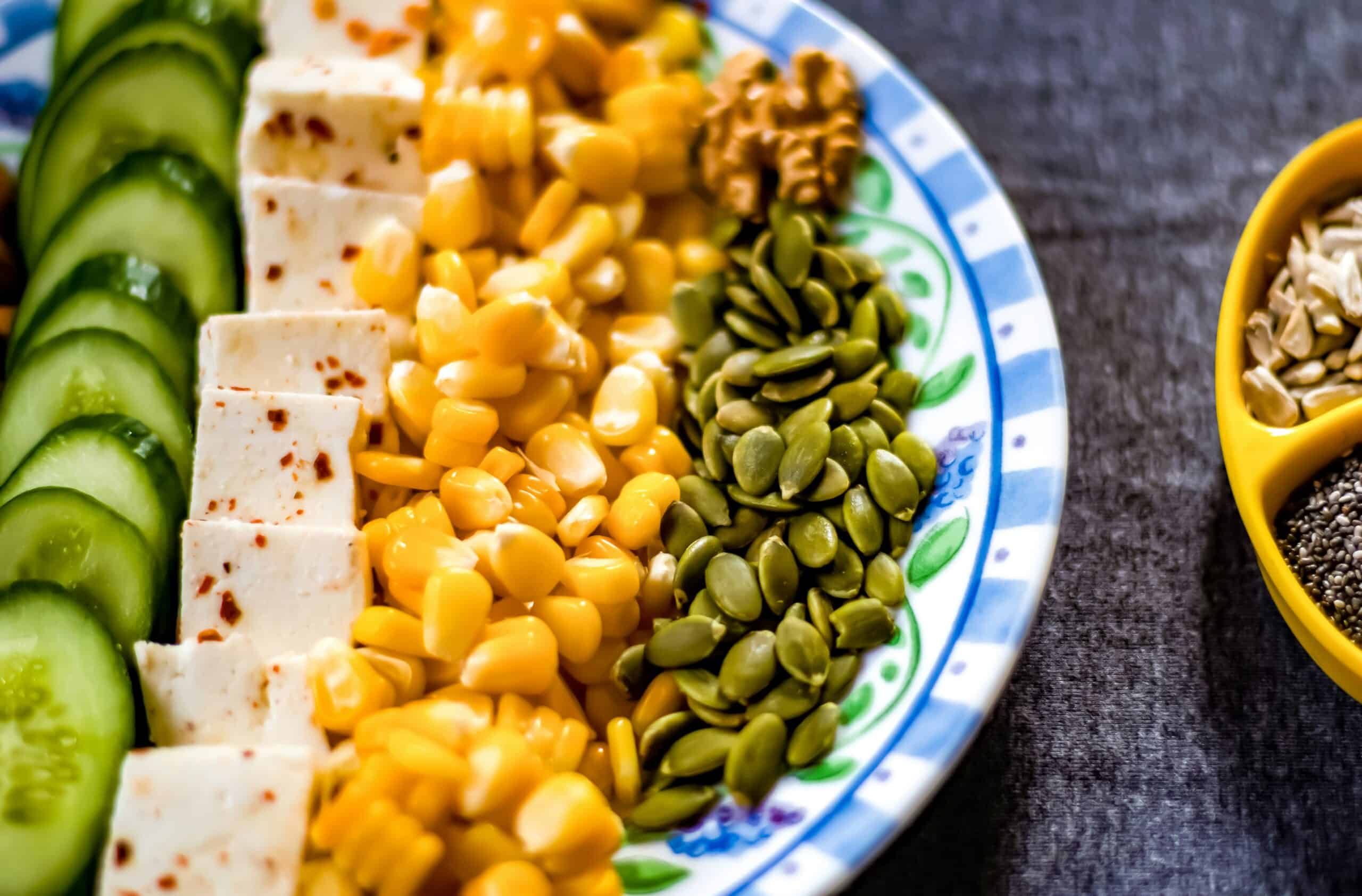A colorful plate featuring tofu, corn, pumpkin seeds, and cucumber, demonstrating ways to incorporate soy into a balanced diet for managing endometriosis. - Rachael Haverland Site A colorful plate featuring tofu, corn, pumpkin seeds, and cucumber, demonstrating ways to incorporate soy into a balanced diet for managing endometriosis.