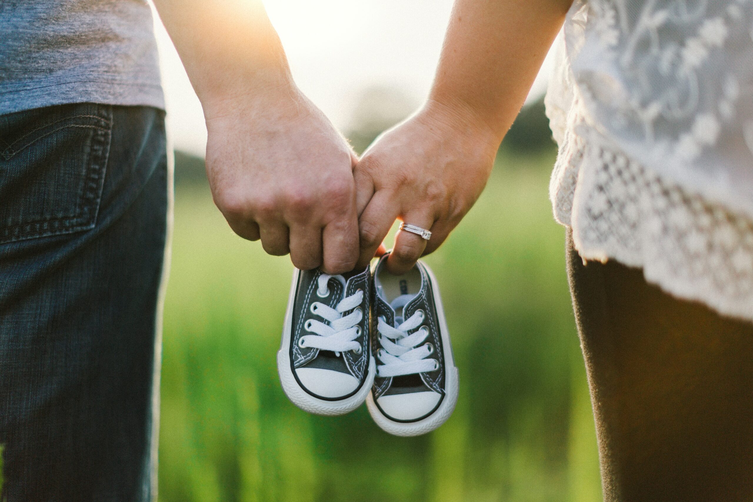 a couple holding tiny baby shoes in a field - Rachael Haverland Site a couple holding tiny baby shoes in a field