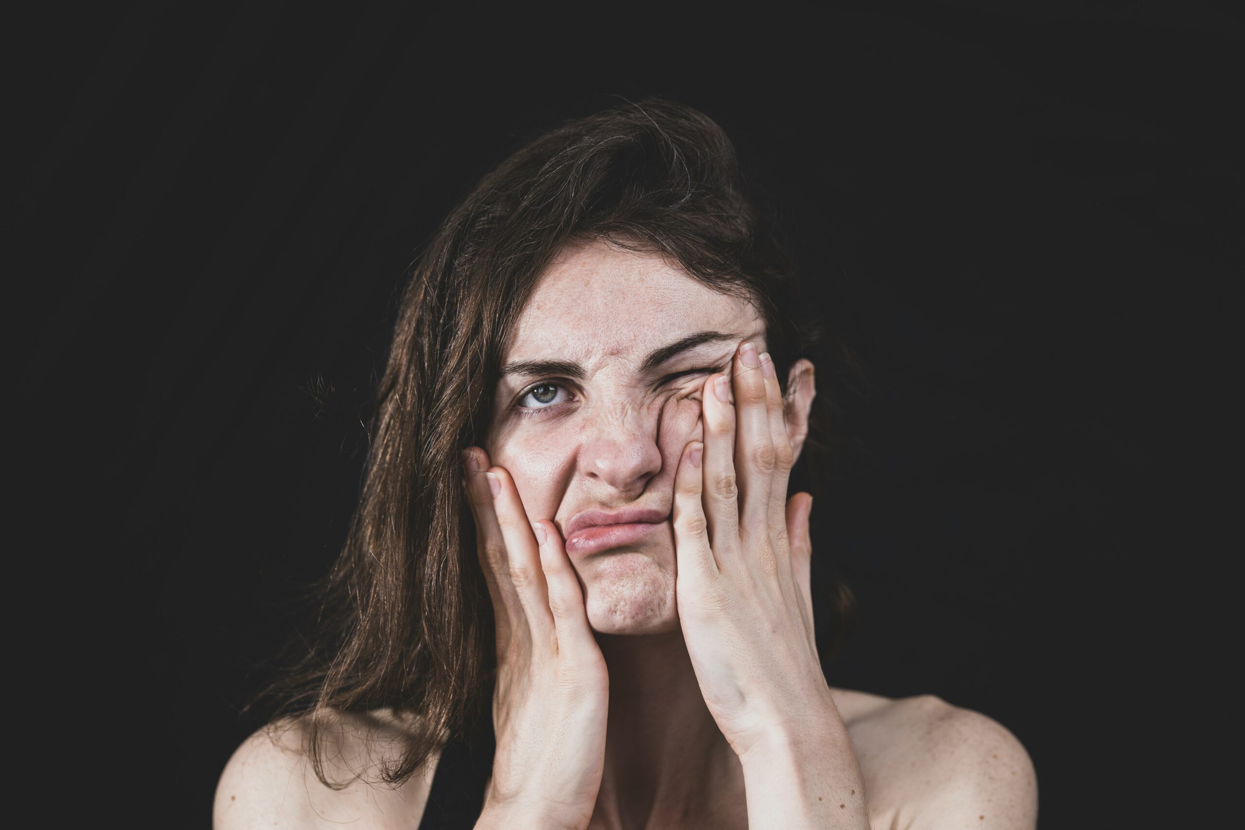 Woman pressing her face in visible frustration, capturing the emotional toll and mood changes tied to hormonal fluctuations from endometriosis. - Rachael Haverland Site Woman pressing her face in visible frustration, capturing the emotional toll and mood changes tied to hormonal fluctuations from endometriosis.