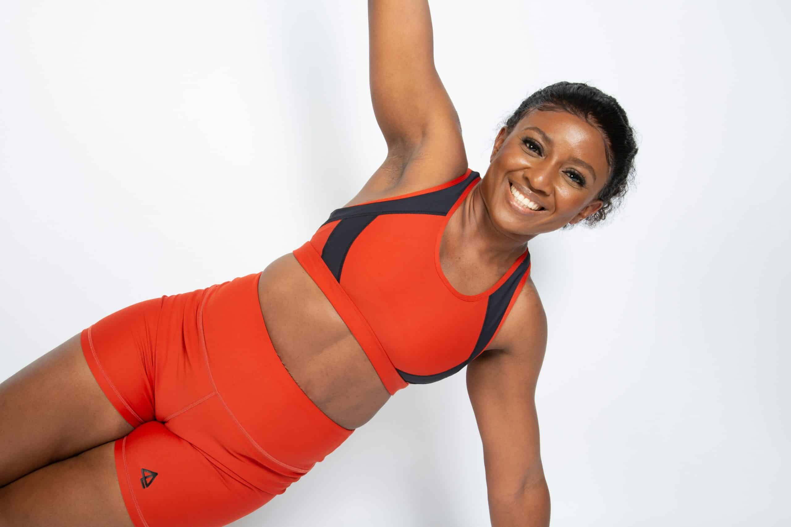 A smiling woman holds a side plank pose in athletic wear, representing strength, confidence, and the importance of physical wellness in overall reproductive health. - Rachael Haverland Site A smiling woman holds a side plank pose in athletic wear, representing strength, confidence, and the importance of physical wellness in overall reproductive health.