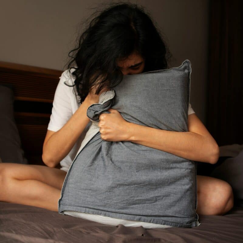 woman with messy hair holding on to a pillow