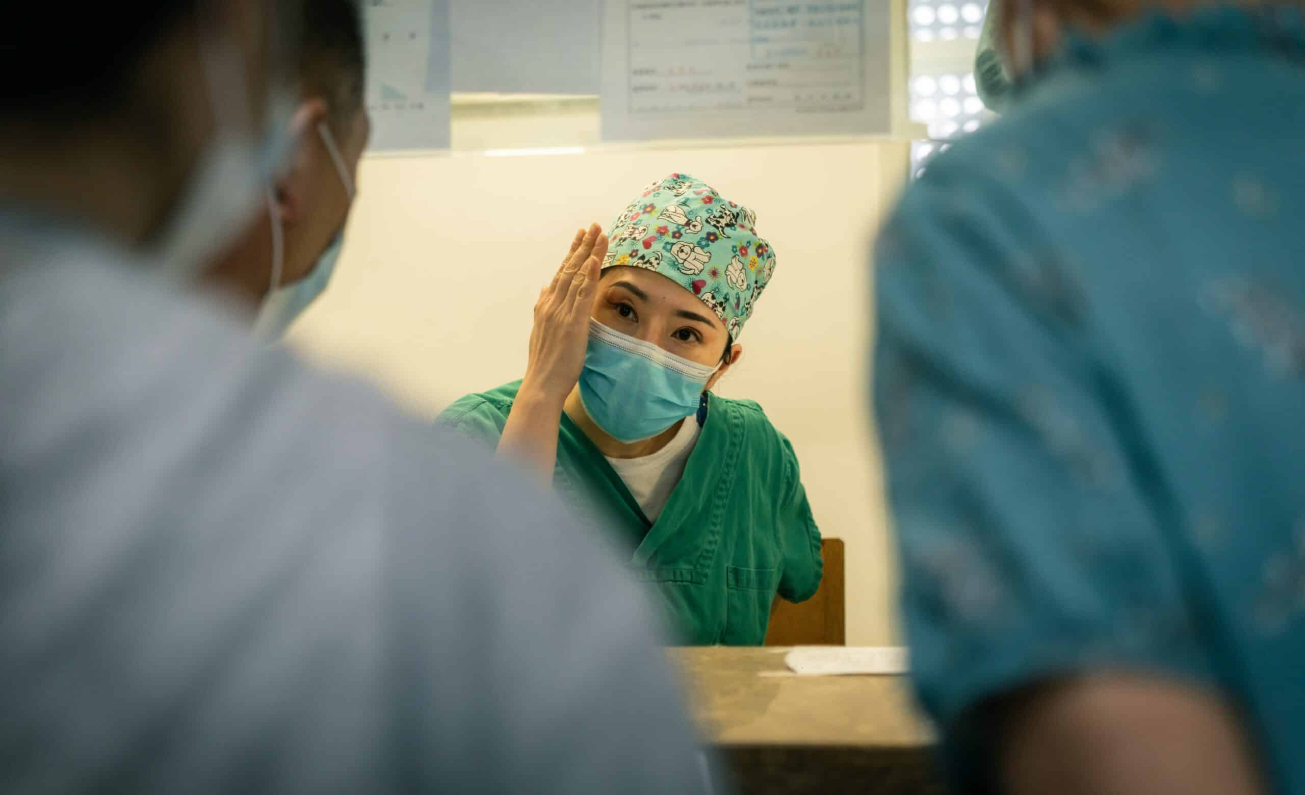 Female surgeon in scrubs and mask consulting with patient - Rachael Haverland Site Female surgeon in scrubs and mask consulting with patient