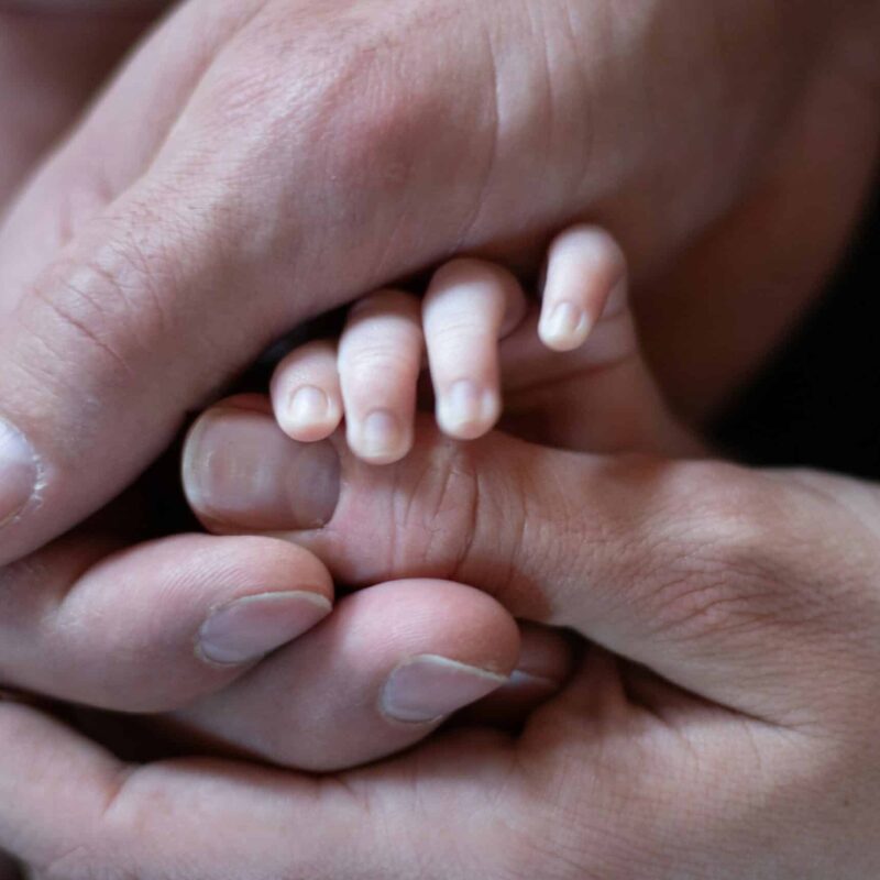 a woman holding a new born baby's hand