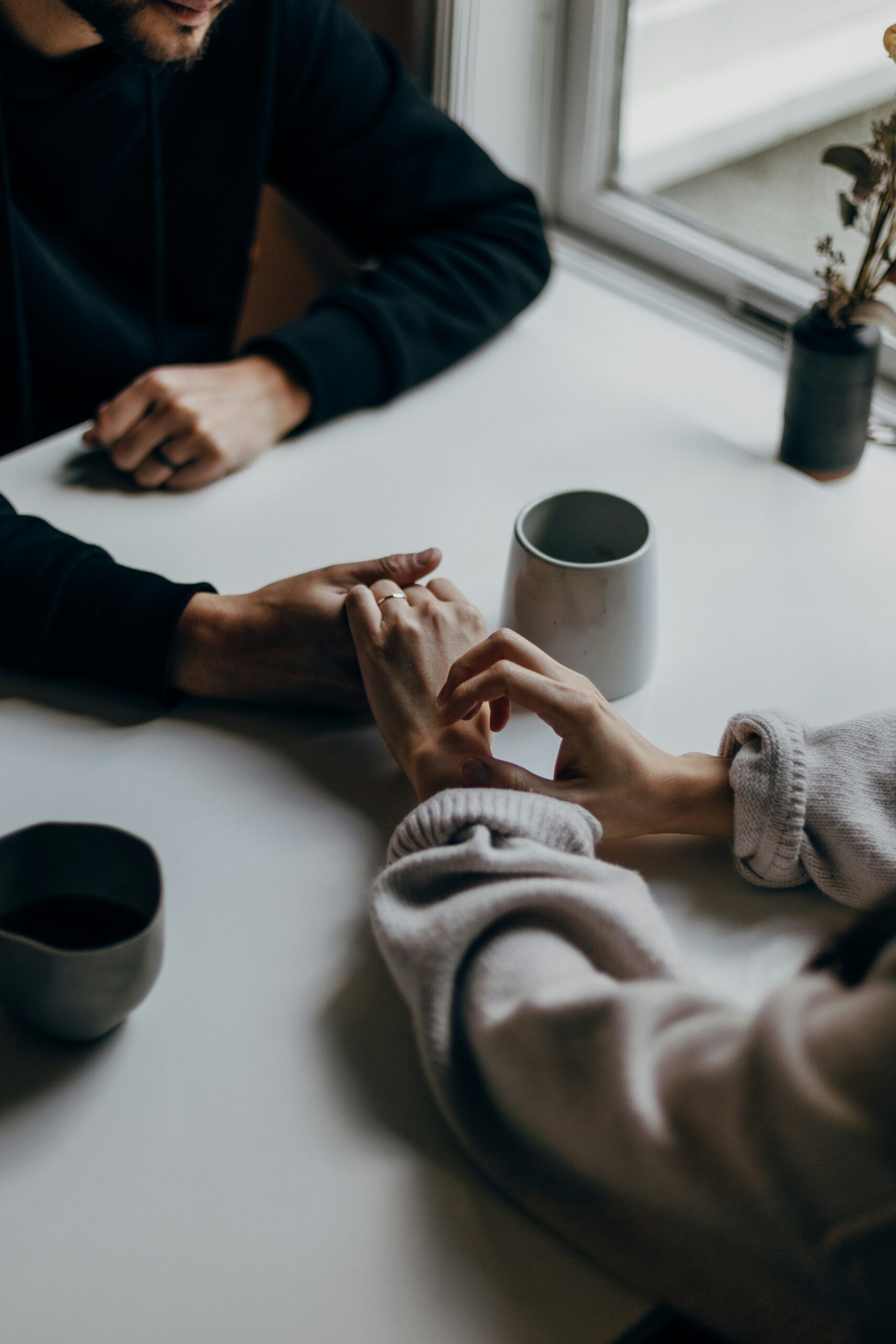 Close-up of a couple holding hands at a table with coffee mugs - Rachael Haverland Site Close-up of a couple holding hands at a table with coffee mugs