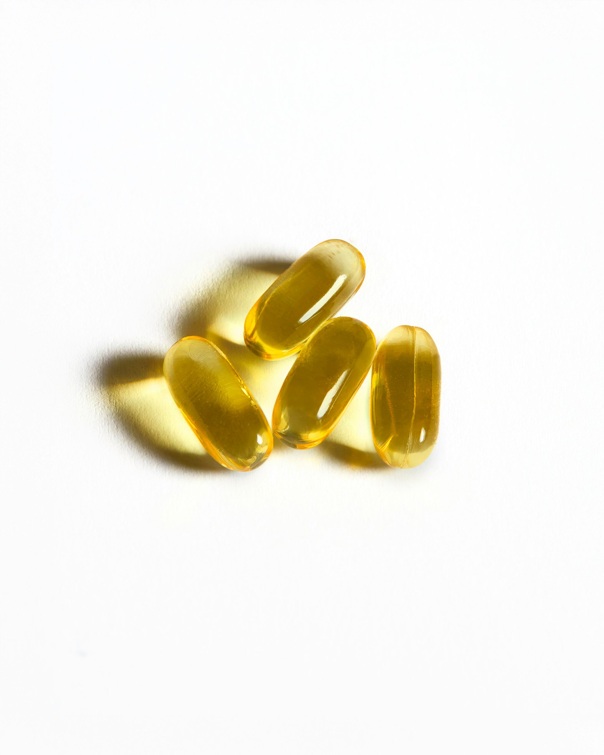 A close-up of four golden omega-3 capsules highlights quality supplement choices for managing endometriosis. - Rachael Haverland Site A close-up of four golden omega-3 capsules highlights quality supplement choices for managing endometriosis.