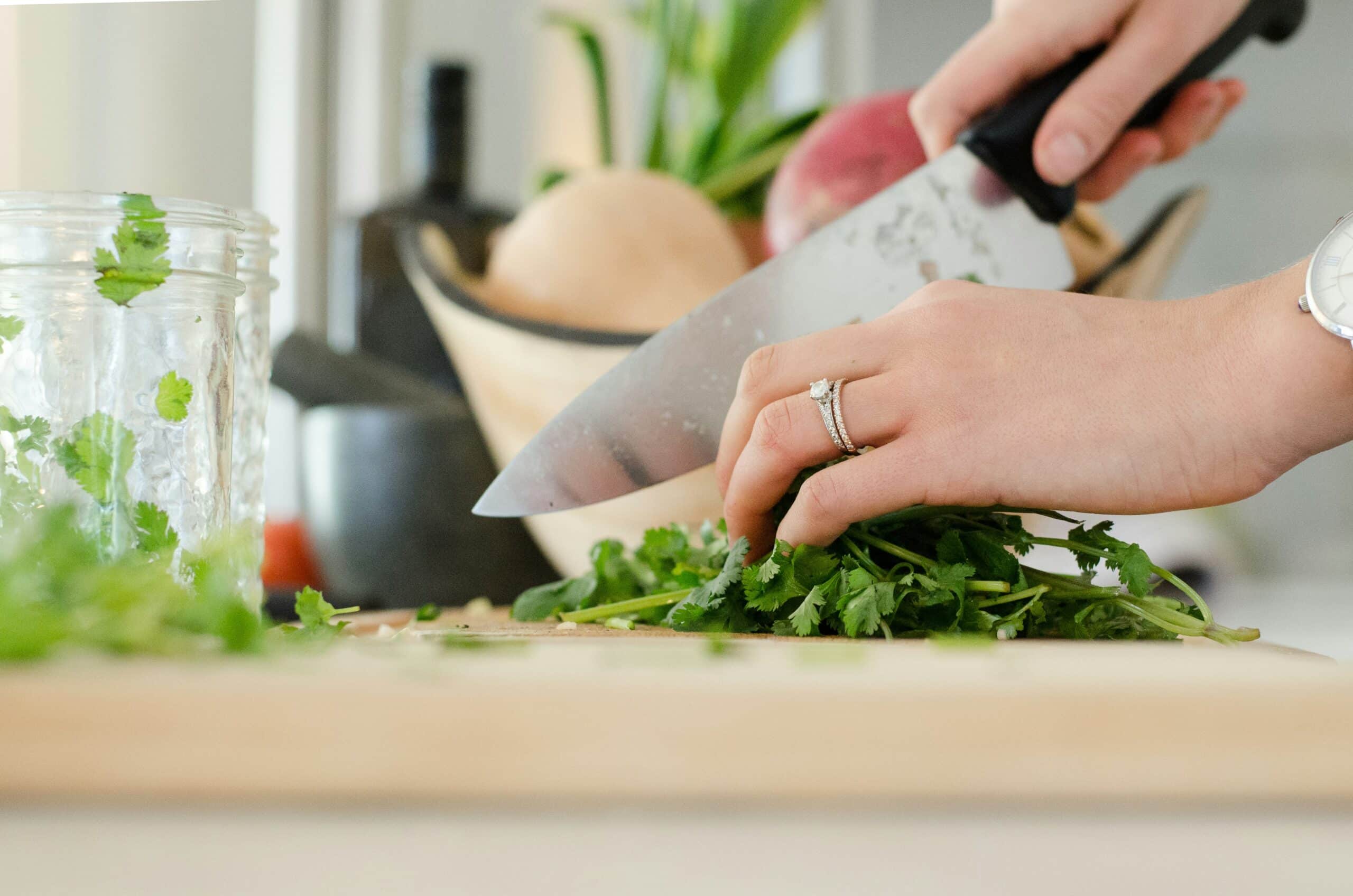 Close-up of hands chopping fresh herbs in a bright kitchen, representing healthy meal prep for endometriosis-friendly recipes. - Rachael Haverland Site Close-up of hands chopping fresh herbs in a bright kitchen, representing healthy meal prep for endometriosis-friendly recipes.