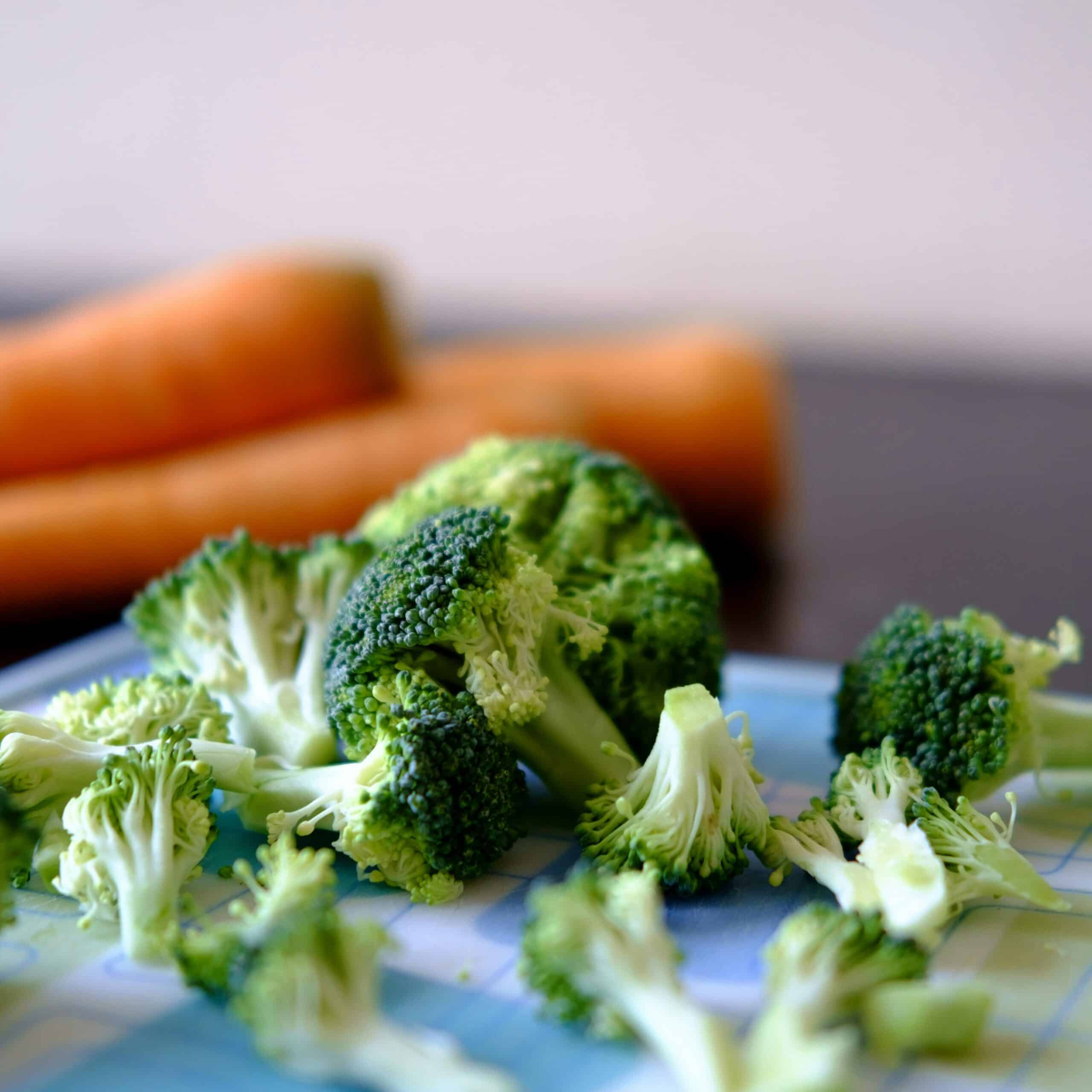 Fresh broccoli florets and whole carrots on a kitchen surface, showcasing nutrient-rich vegetables that support endometriosis relief. - Rachael Haverland Site Fresh broccoli florets and whole carrots on a kitchen surface, showcasing nutrient-rich vegetables that support endometriosis relief.