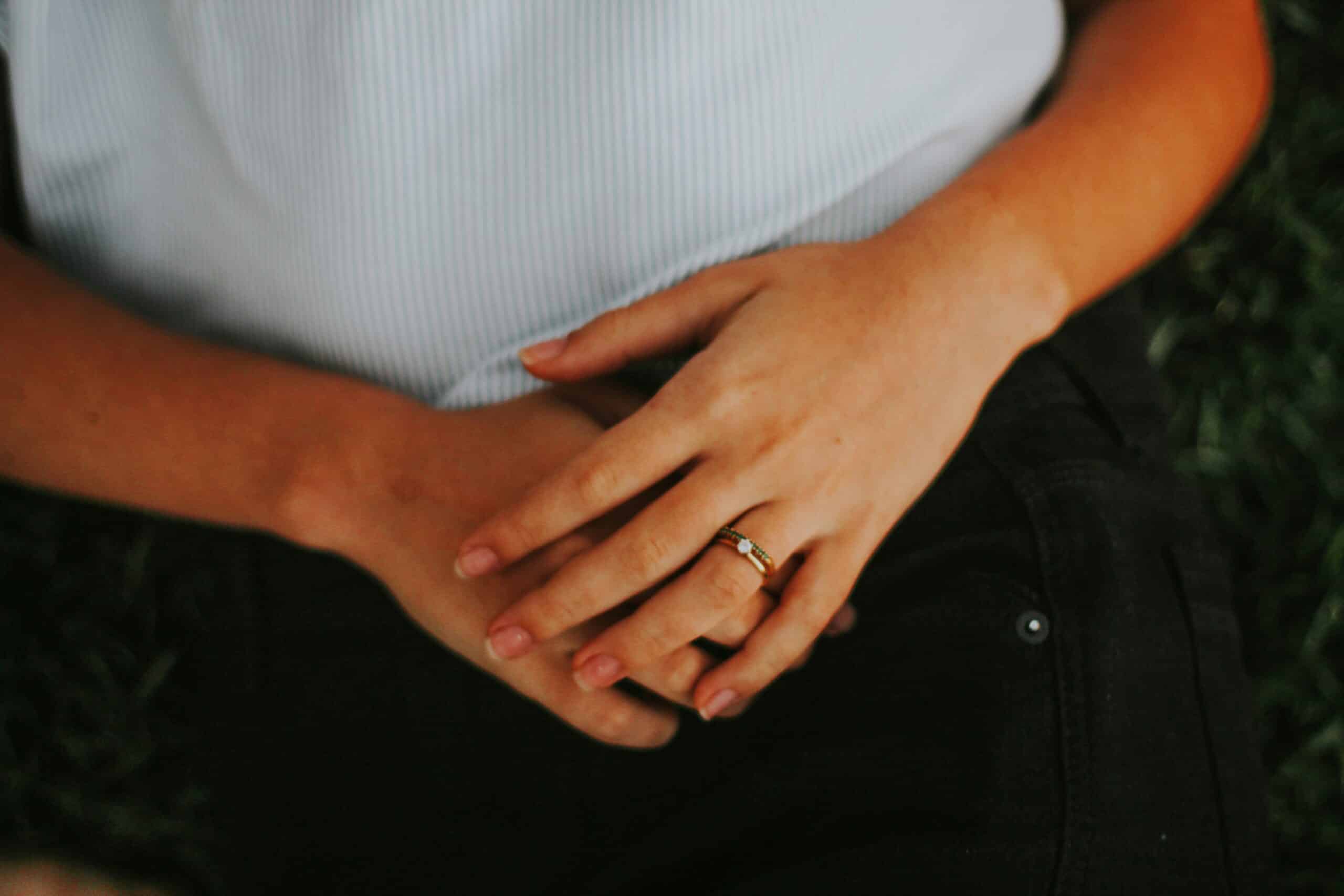 Close-up of a person resting their hands over their lower abdomen, indicating abdominal discomfort or bloating. - Rachael Haverland Site Close-up of a person resting their hands over their lower abdomen, indicating abdominal discomfort or bloating.