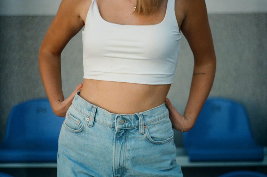 a woman wearing a tank top and jeans