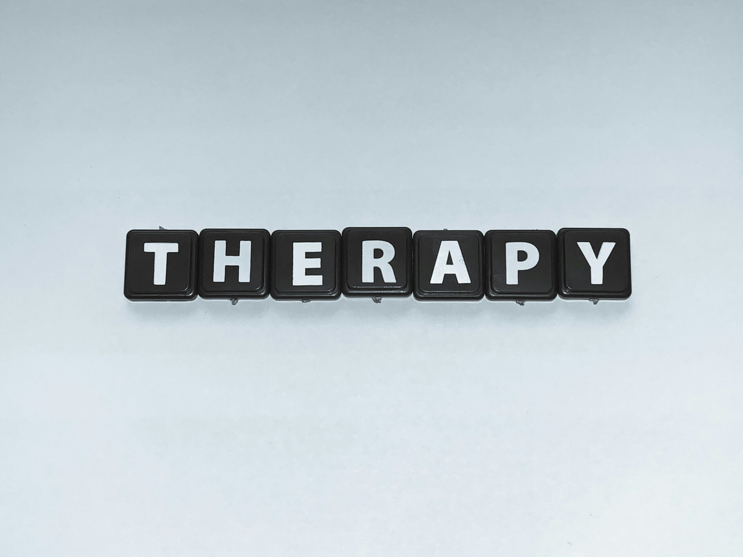 Black tiles spell out the word "THERAPY" on a light background, symbolizing accessible mental health support options for individuals managing endometriosis.