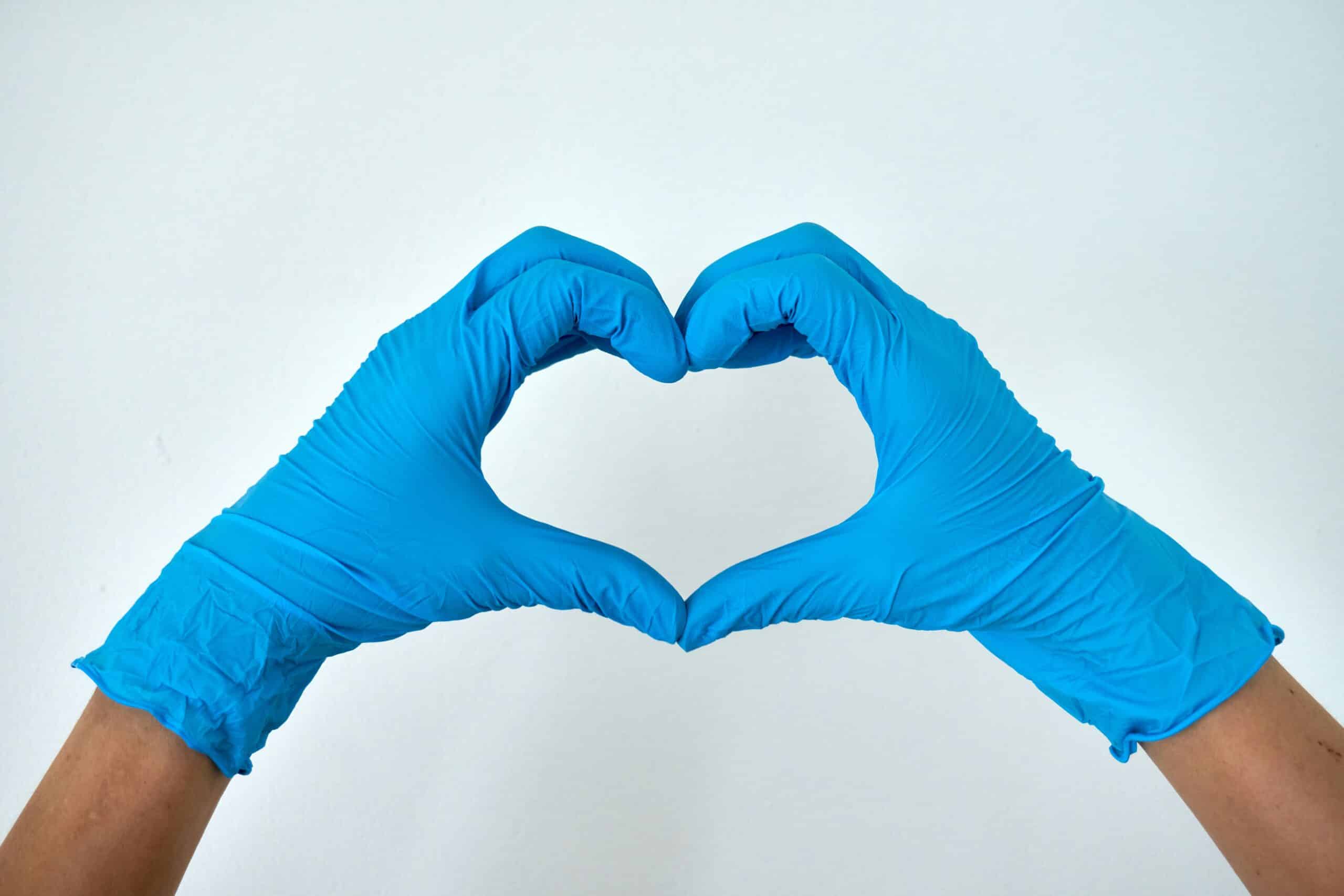 Hands in blue medical gloves forming a heart shape, symbolizing care and compassion in the context of endometriosis awareness and treatment.