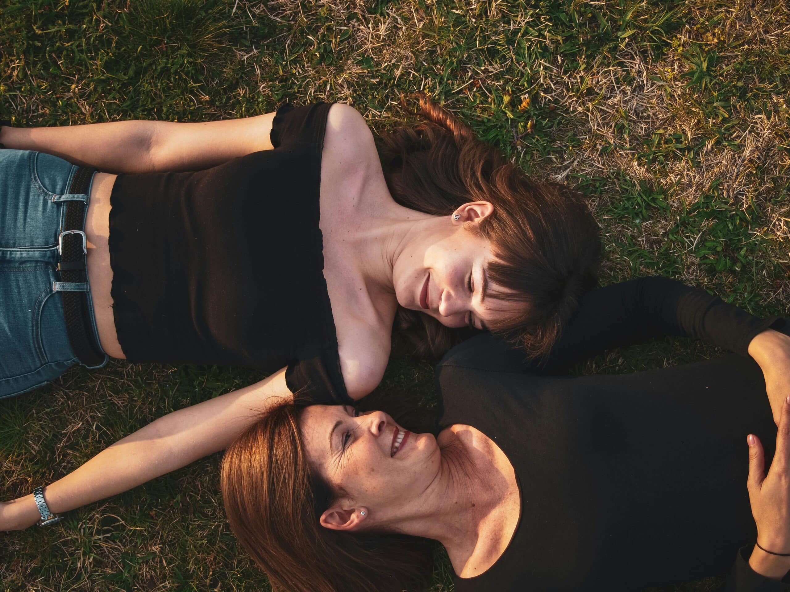 a mother daughter duo laying on grass