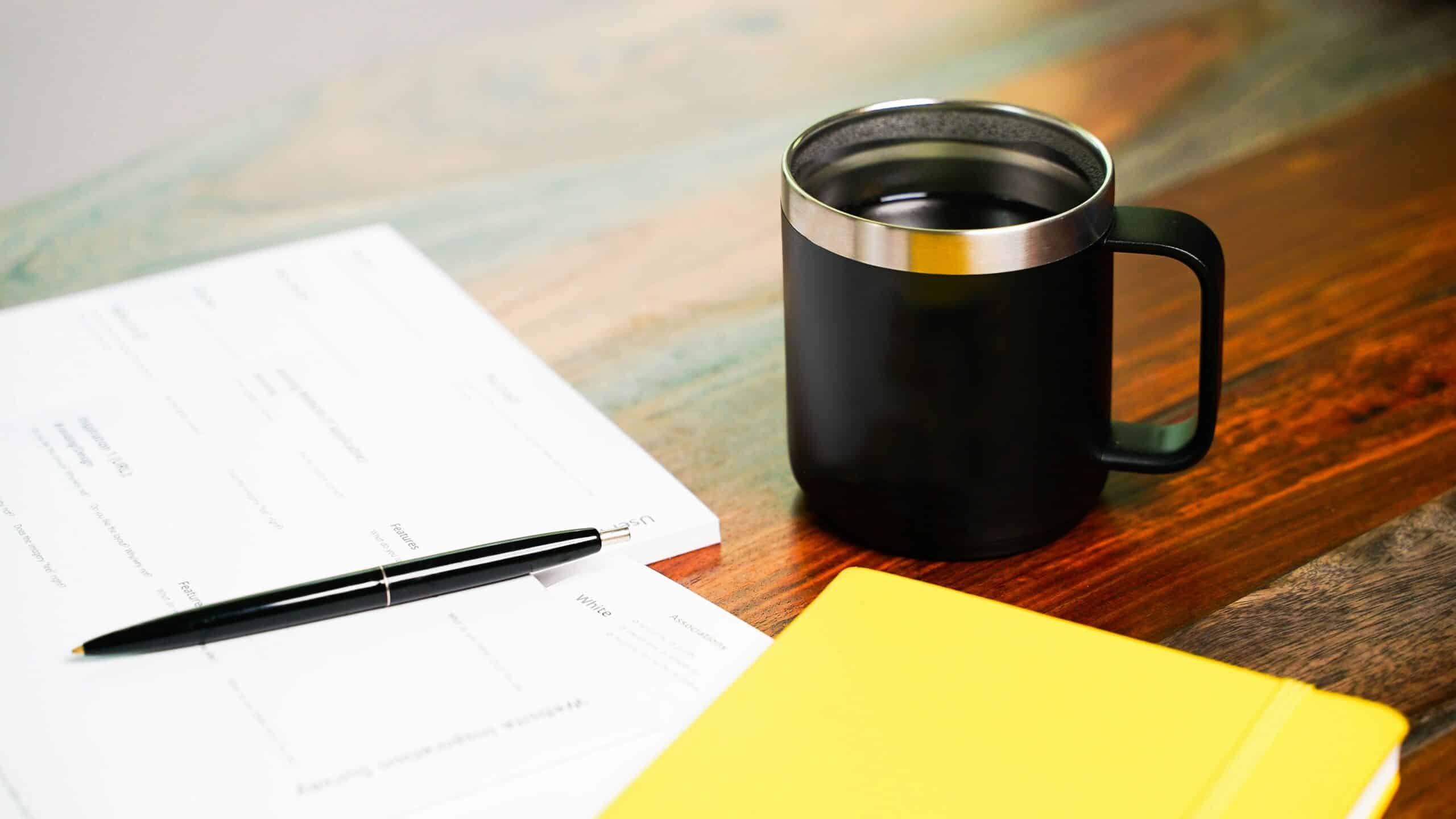 papers and a notebook with pen of a desk