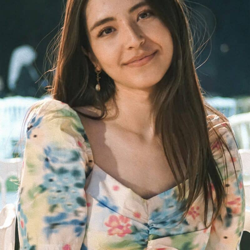 Smiling woman with long hair wearing a floral dress, representing empowerment and support for individuals dealing with endometriosis.