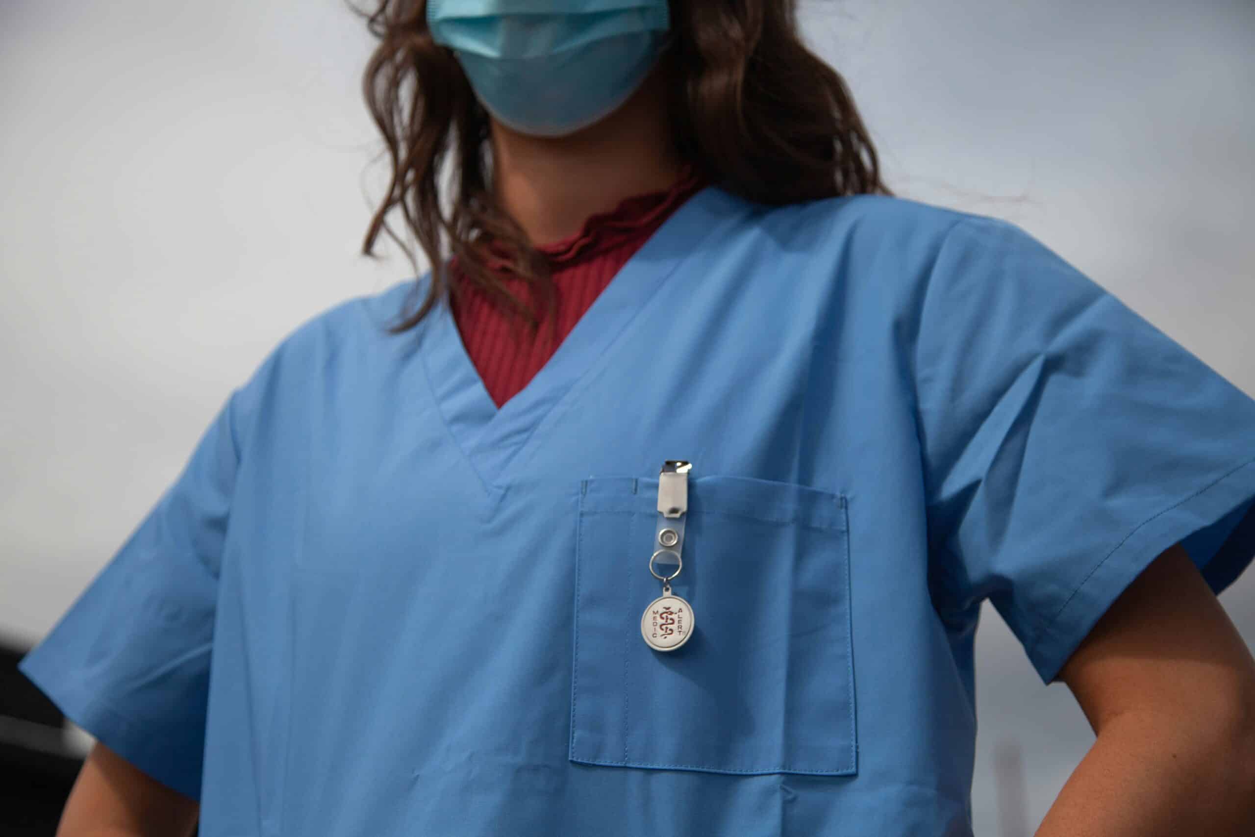 a nurse at the clinic - Rachael Haverland Site Healthcare professional in blue scrubs and face mask, displaying a medical badge, symbolizing patient care and surgical support in endometriosis treatment.