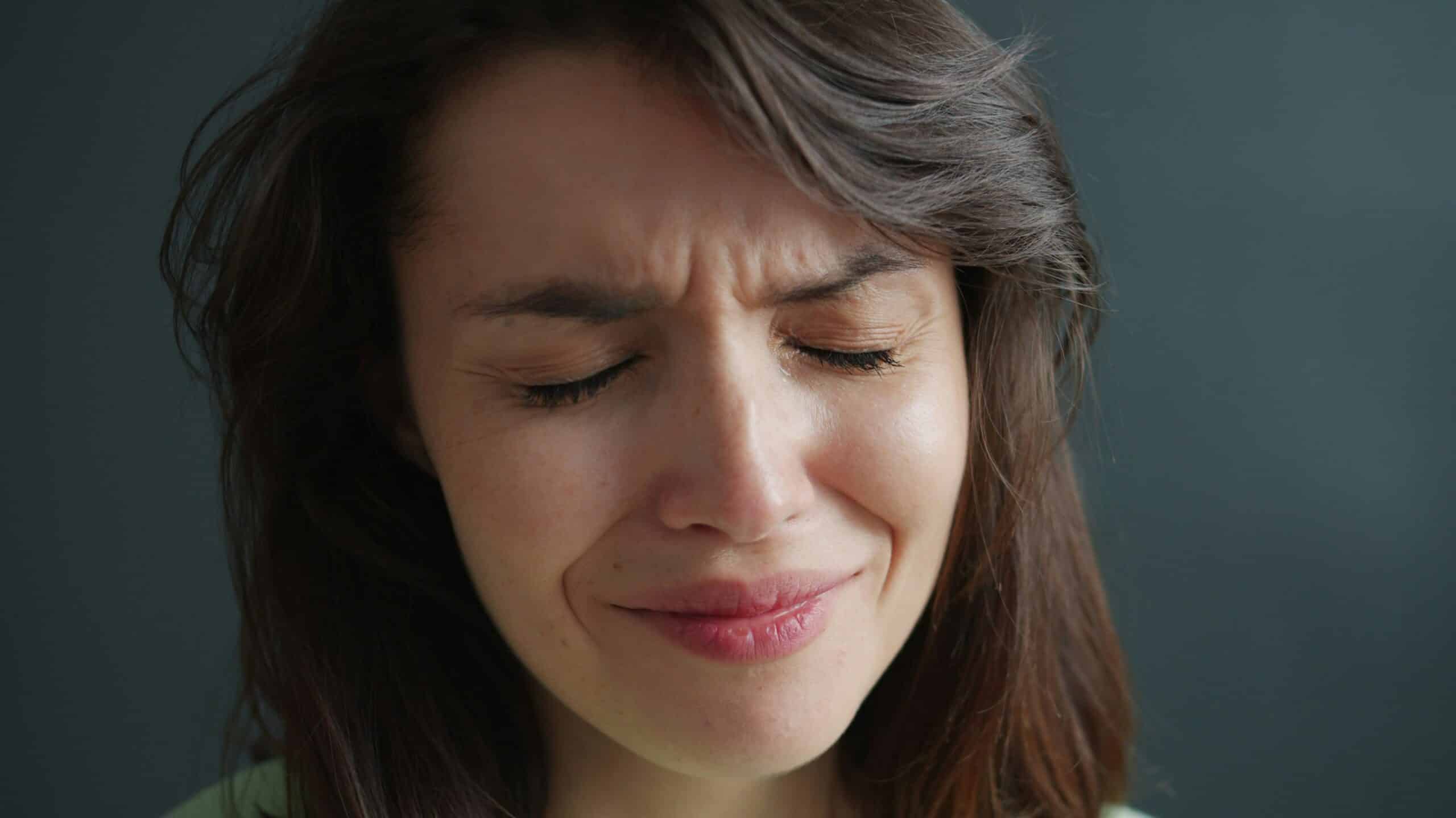 Woman with a pained expression, reflecting emotional distress, relevant to discussions on the impact of endometriosis symptoms and mental health in postmenopausal women.