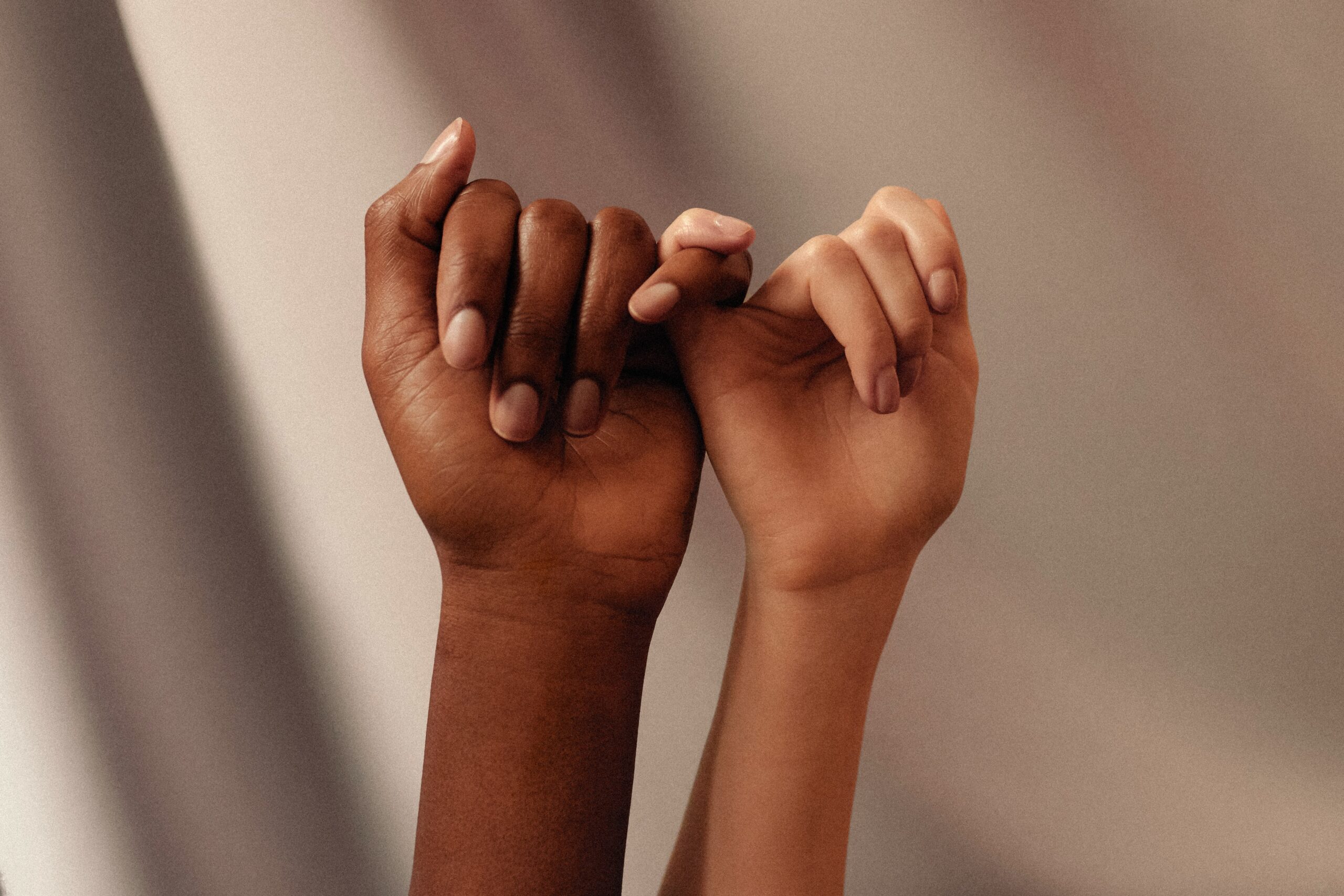 Hands of different skin tones interlocked, symbolizing support and unity, relevant to discussions on endometriosis and women's health.