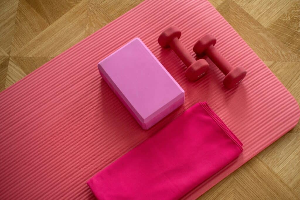 a pink yoga mat with weights and a towel