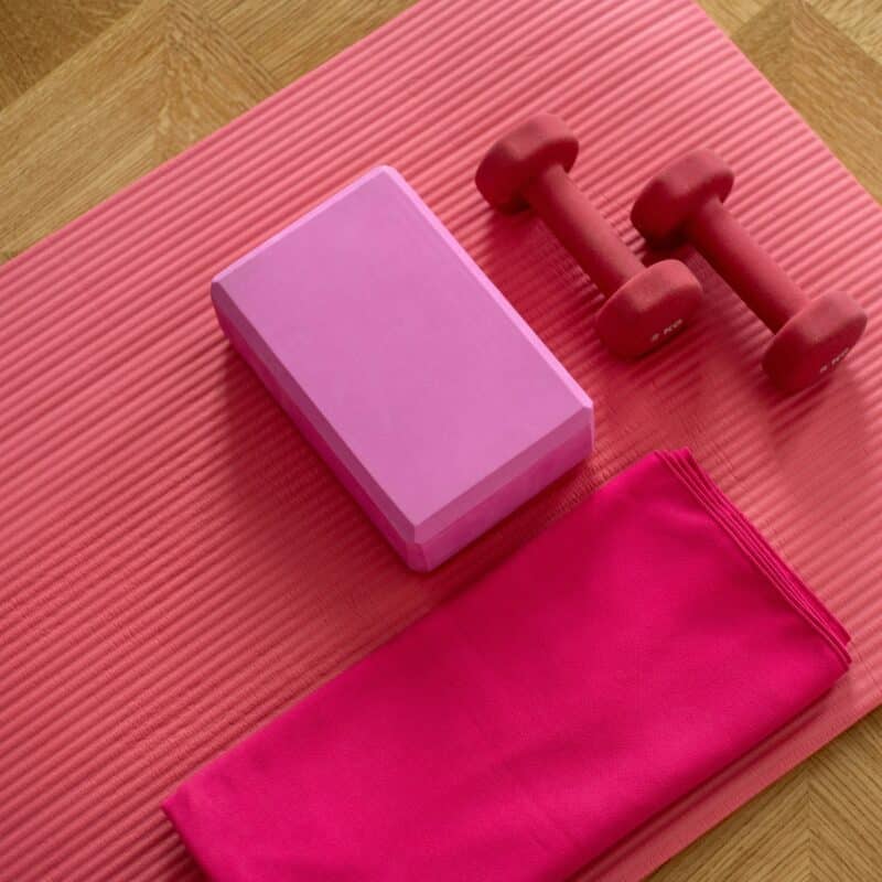 a pink yoga mat with weights and a towel