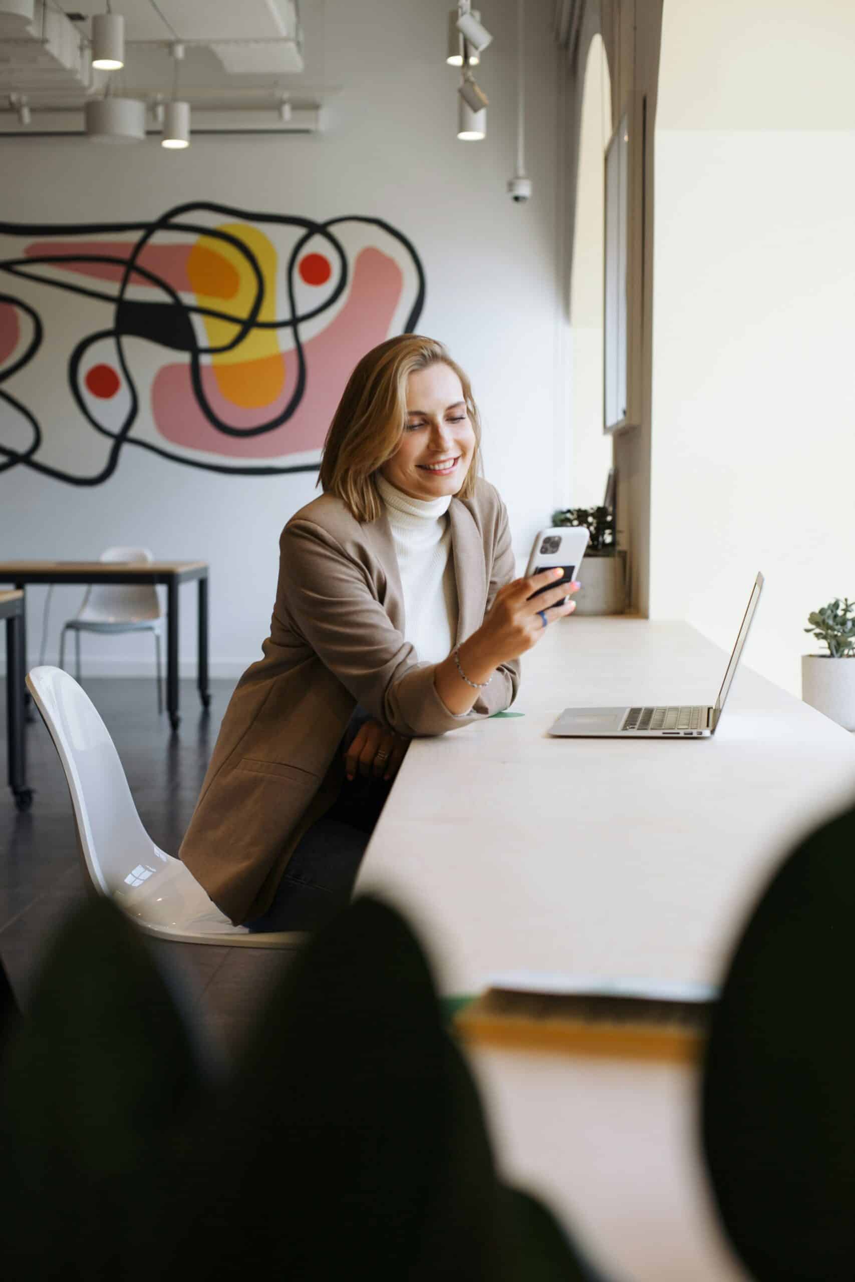 a woman using her phone and laptop