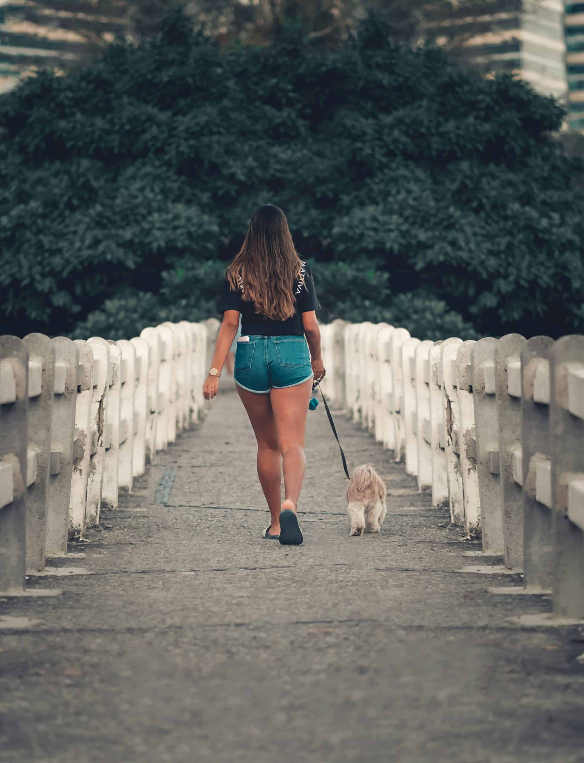 a woman walking - Rachael Haverland Site Woman walking a dog on a pathway, promoting gentle movement and outdoor activity for endometriosis recovery.