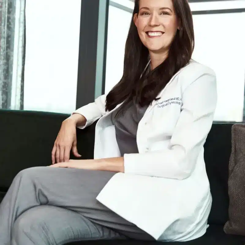 Doctor in a white coat sitting confidently, representing expertise in endometriosis care at the Endometriosis Center of Excellence.