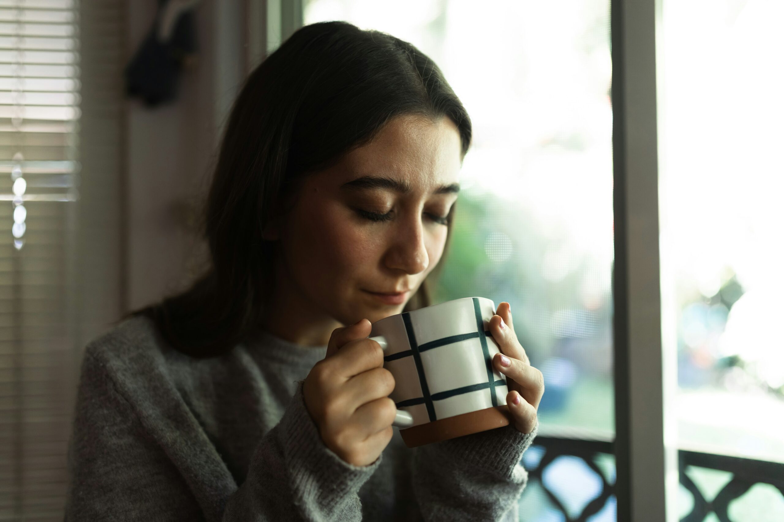 Woman holding a patterned mug, reflecting on pain management and recovery, emphasizing the importance of holistic approaches in pelvic health treatment.
