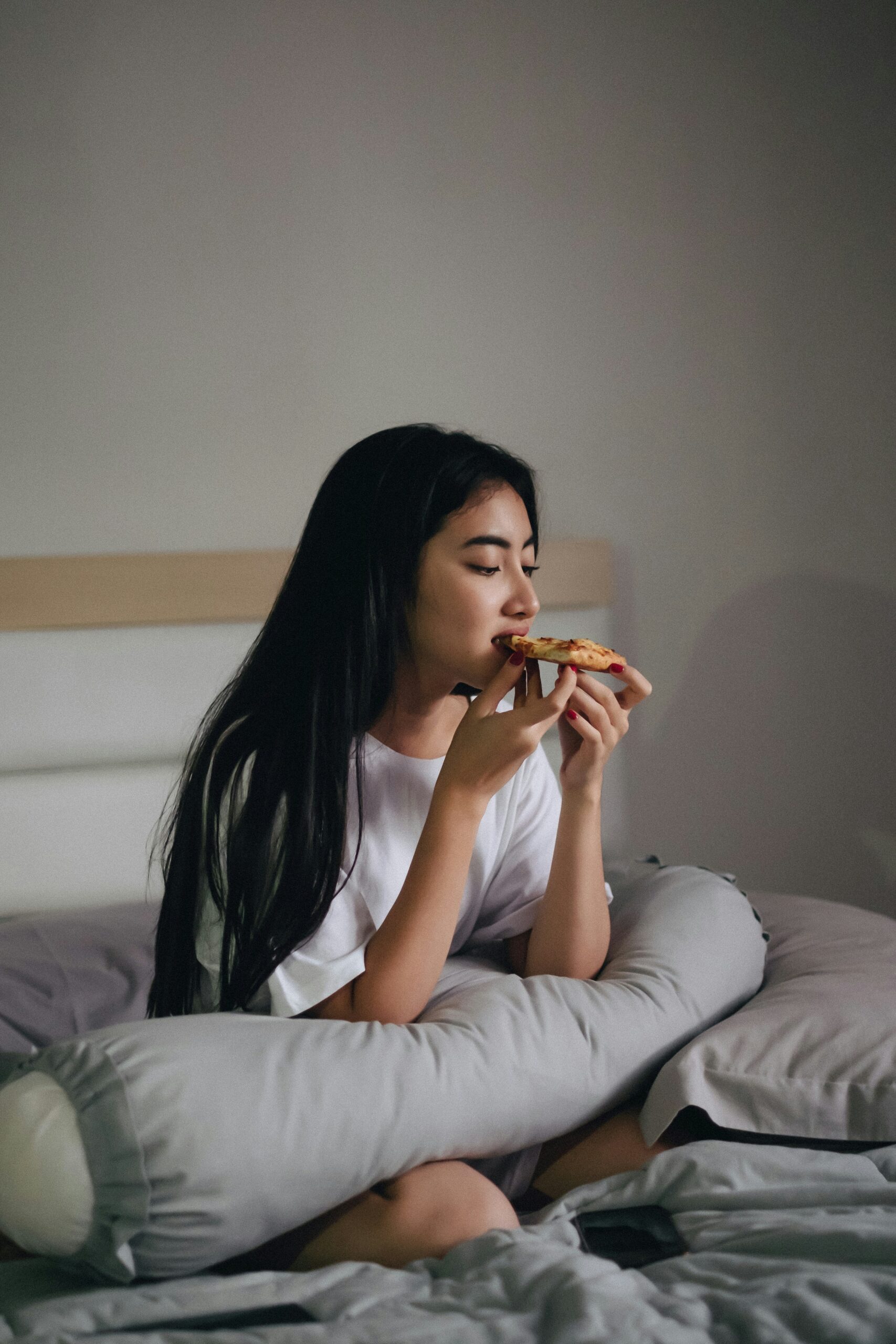 teen girl eating pizza in bed